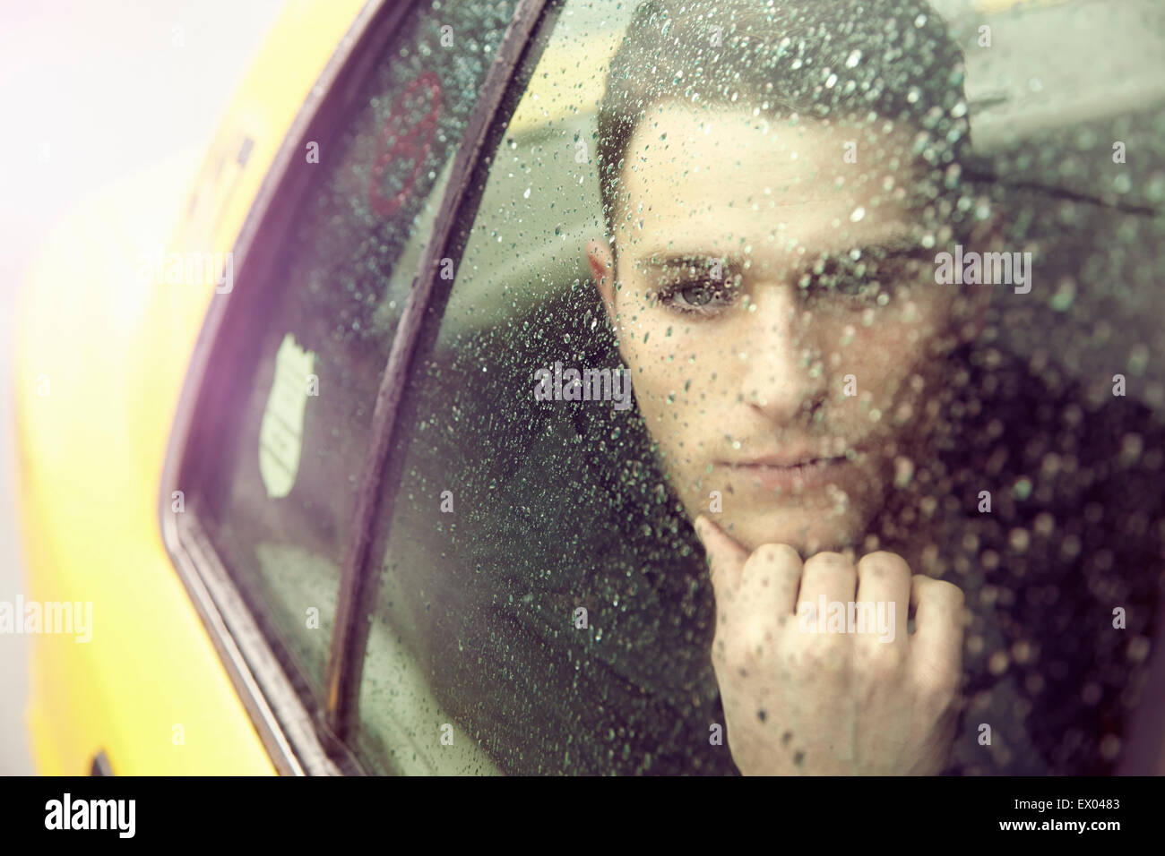 Young man gazing out of yellow cab window in rain Stock Photo