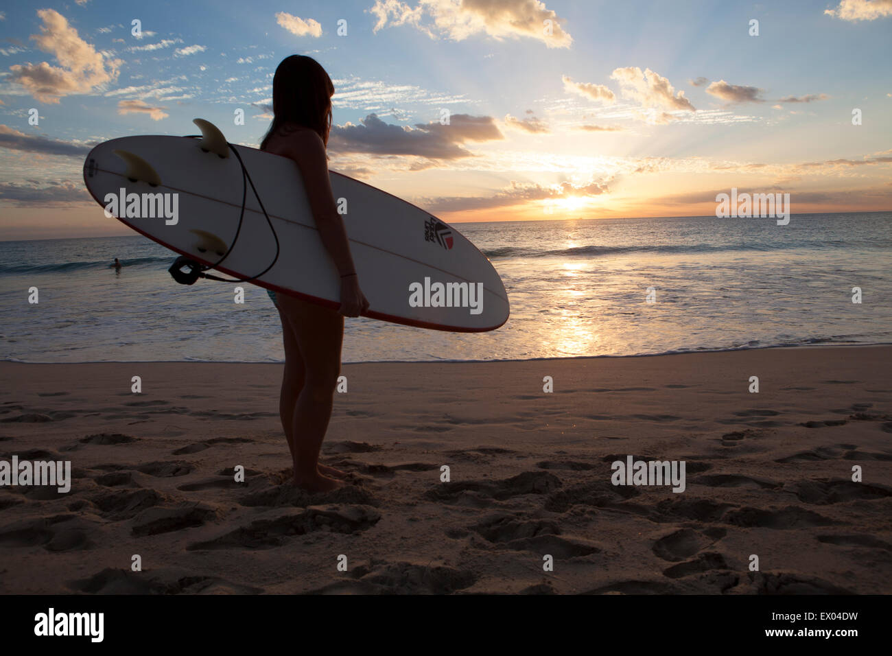 A girl carrying a surfboard on Scarborough Beach in Perth, Western