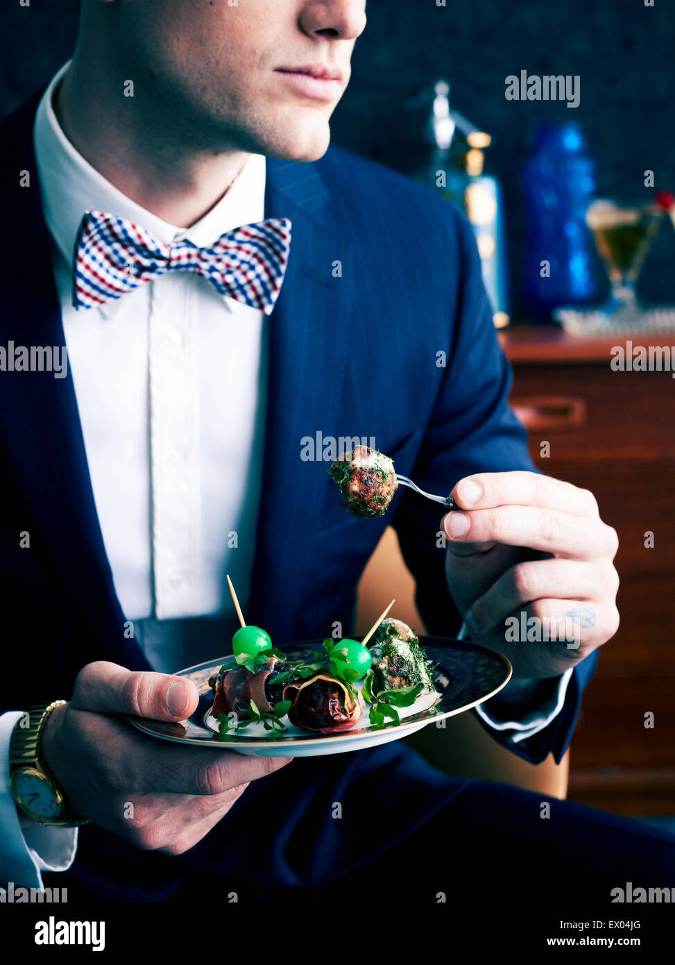 Retro styled man eating plate of appetizers Stock Photo