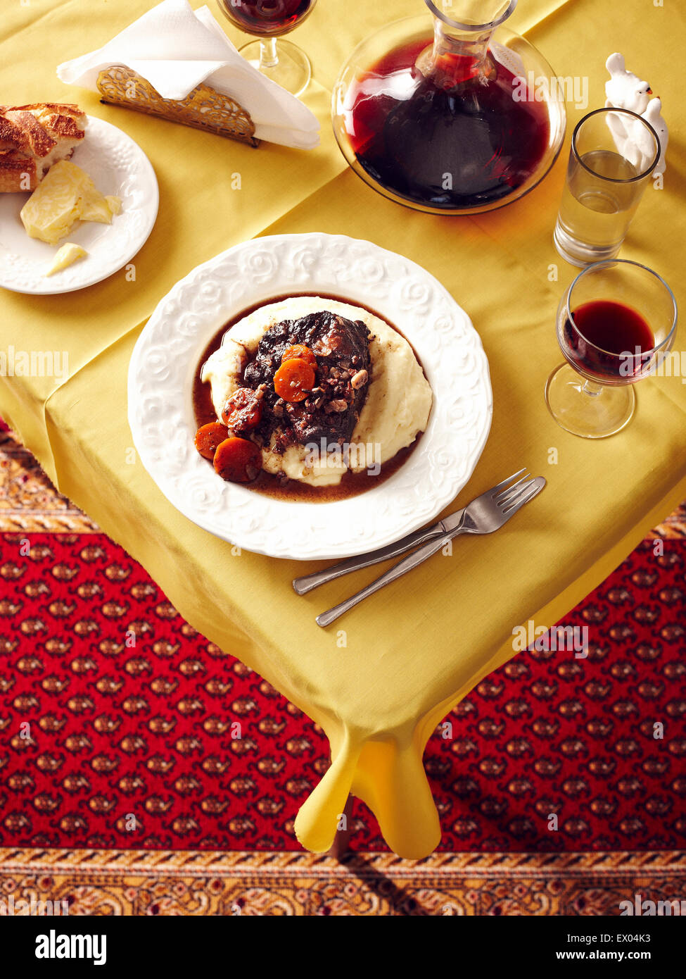 Overhead view of table with beef cheek stew and red wine carafe Stock Photo