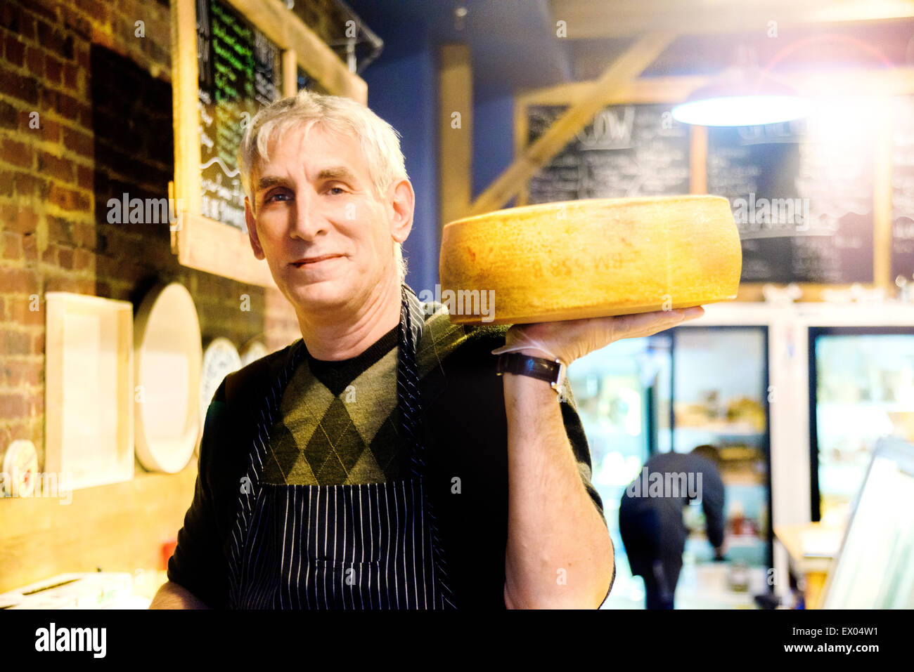 Cheesemonger holding wheel of cheese Stock Photo