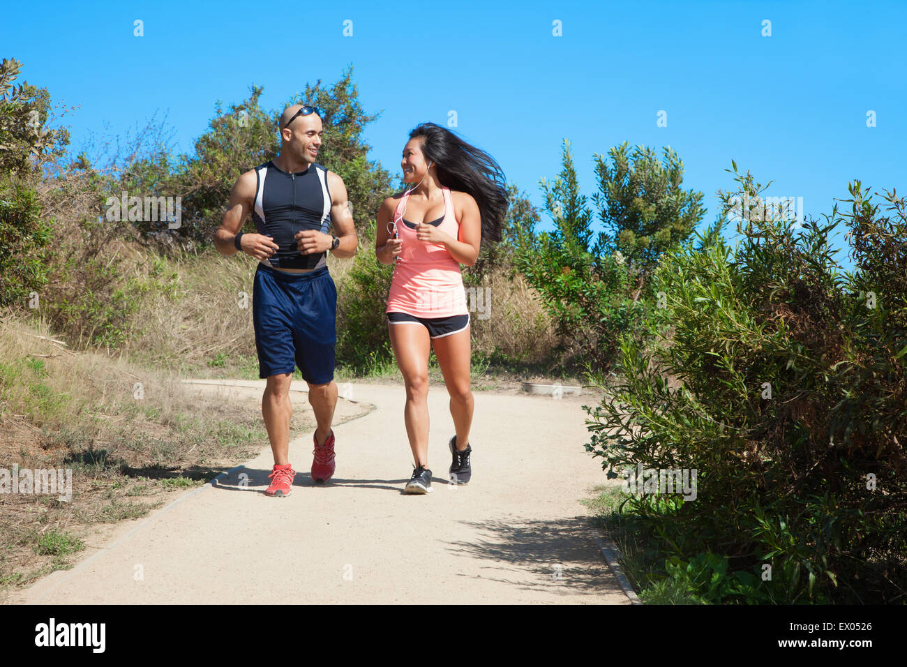 Mid adult man and woman jogging together along rural pathway Stock ...