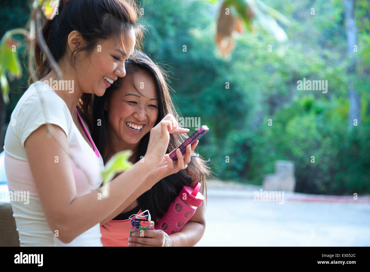 Two mid adult women looking at smartphone together, outdoors Stock Photo