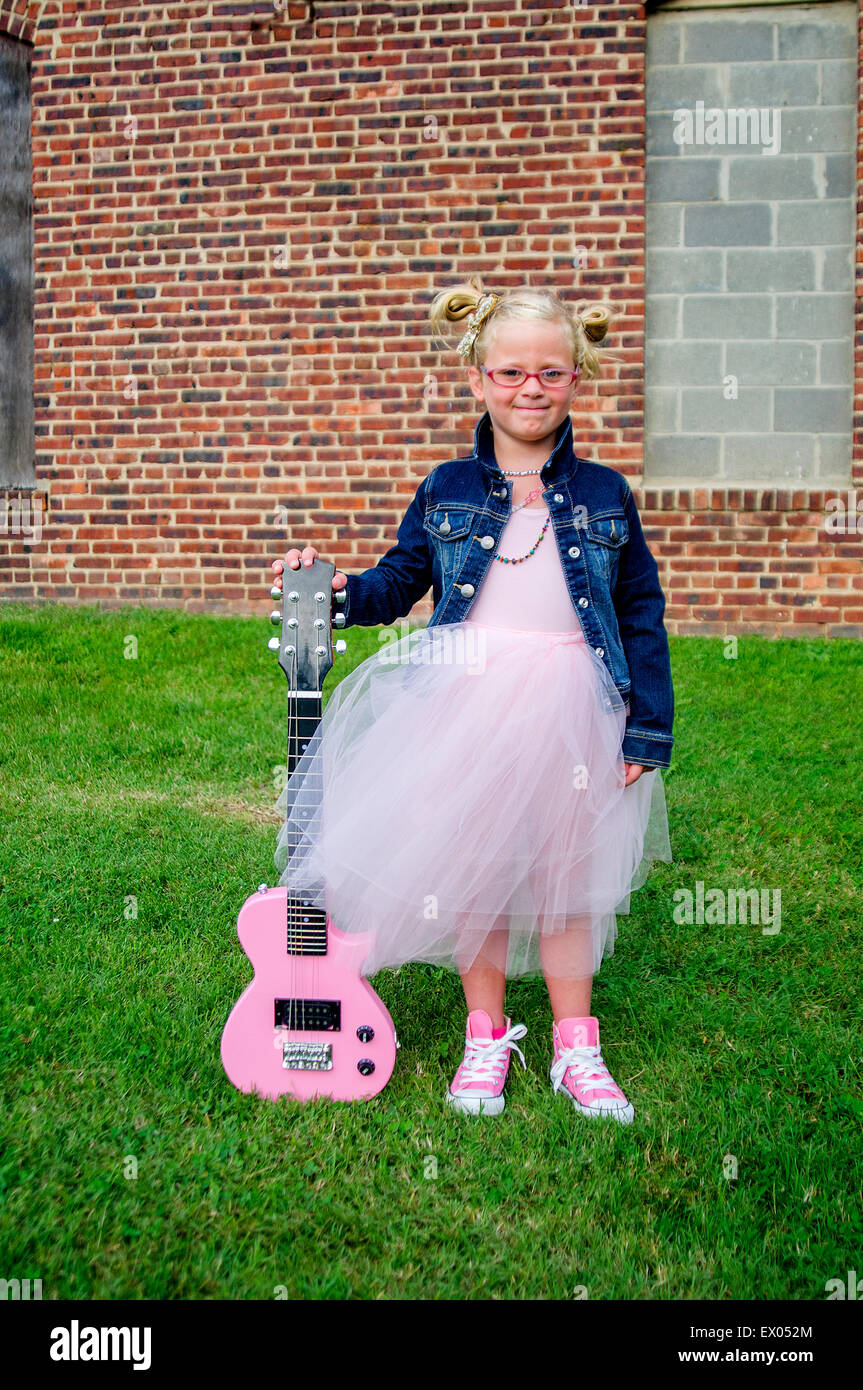 Young girl wearing tutu and denim jacket, holding guitar Stock Photo