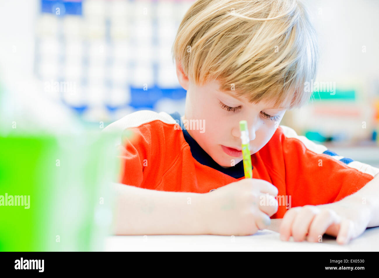 Boy writing in exercise book in classroom Stock Photo