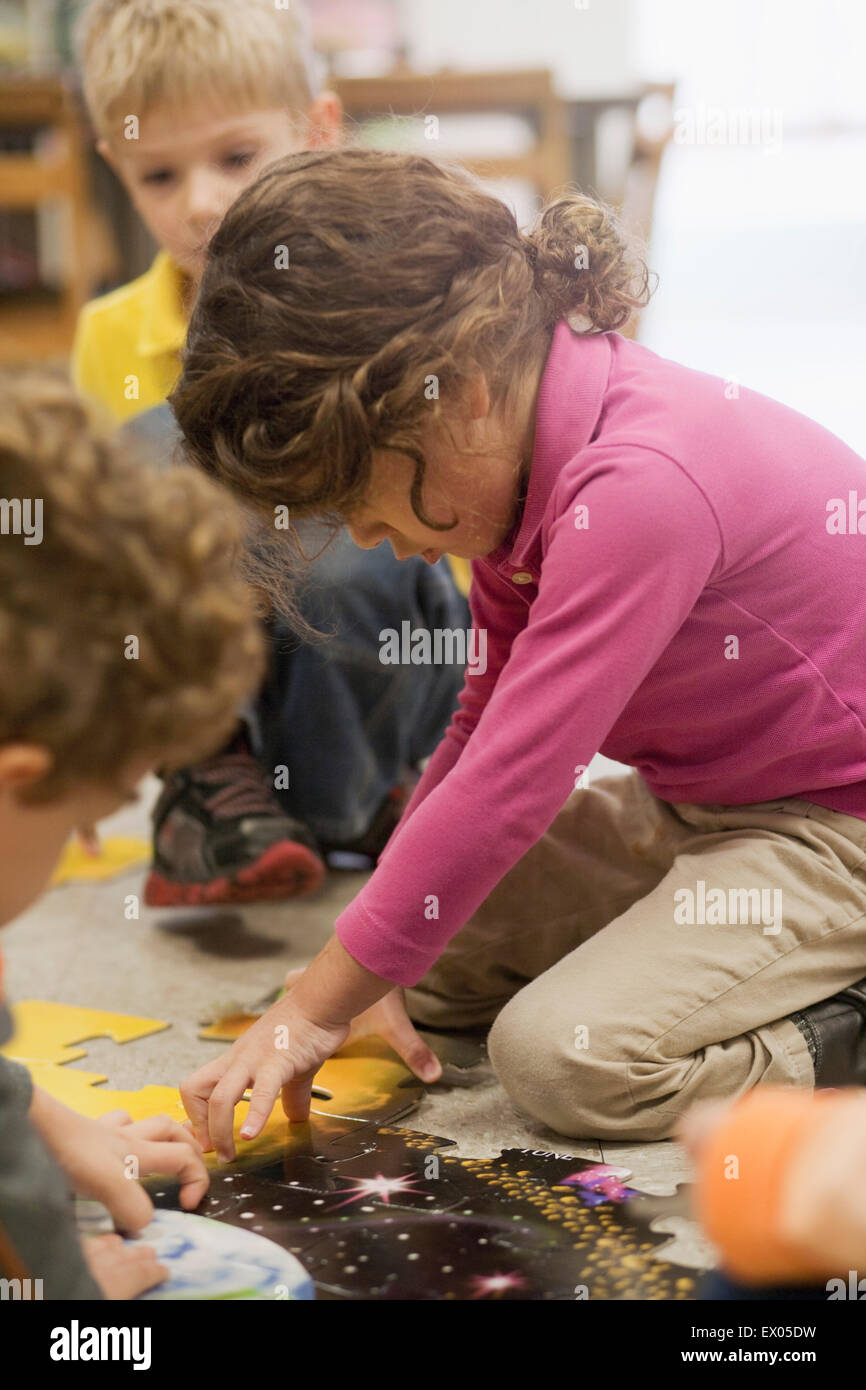 Toddlers playing jigsaw puzzle in classroom Stock Photo Alamy