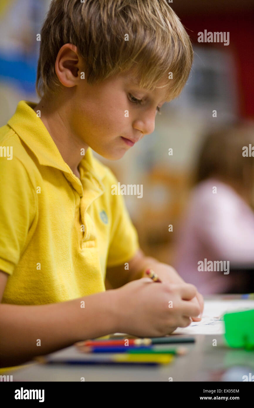 Boy writing in classroom Stock Photo