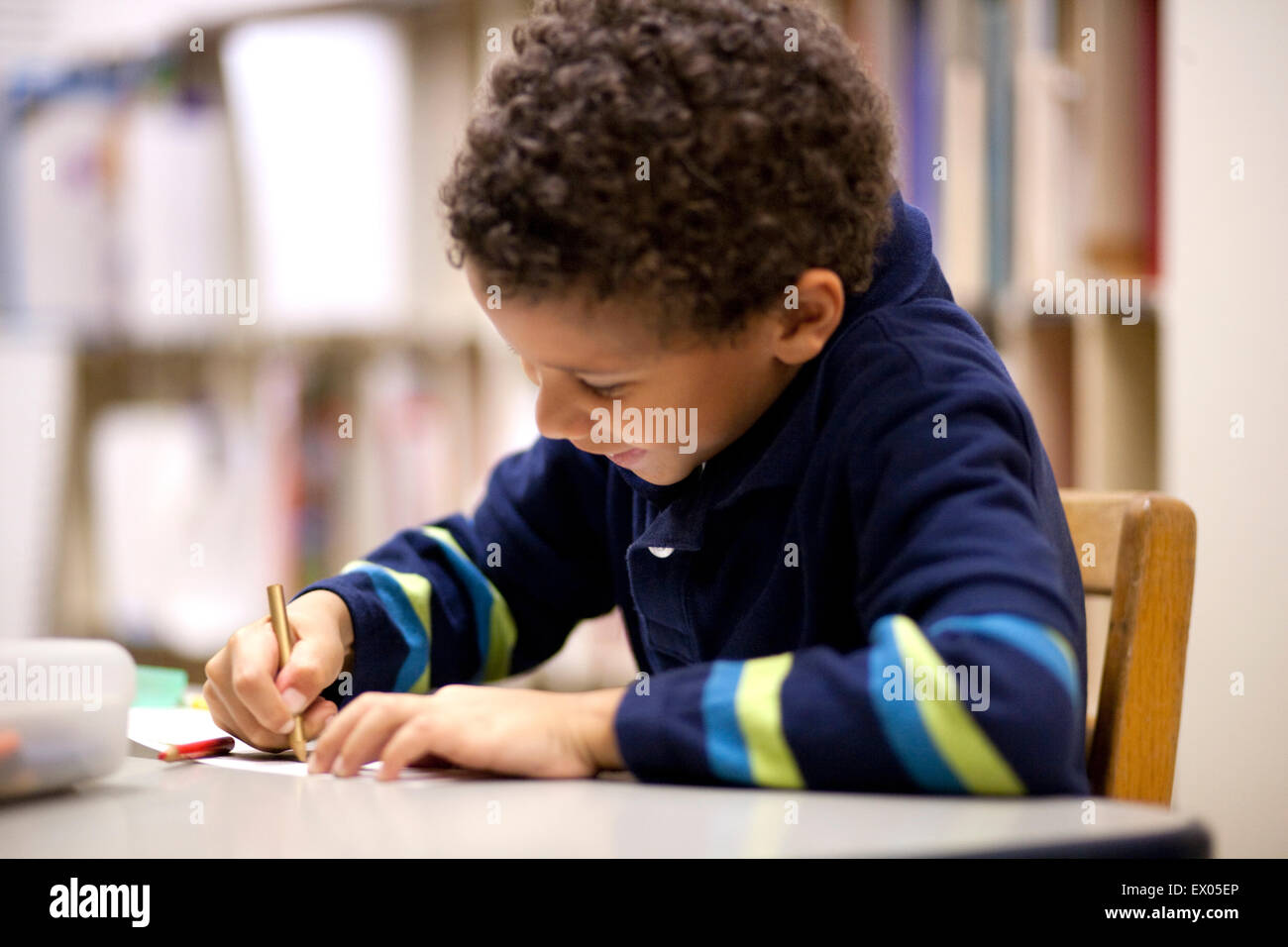 Boy writing in classroom Stock Photo