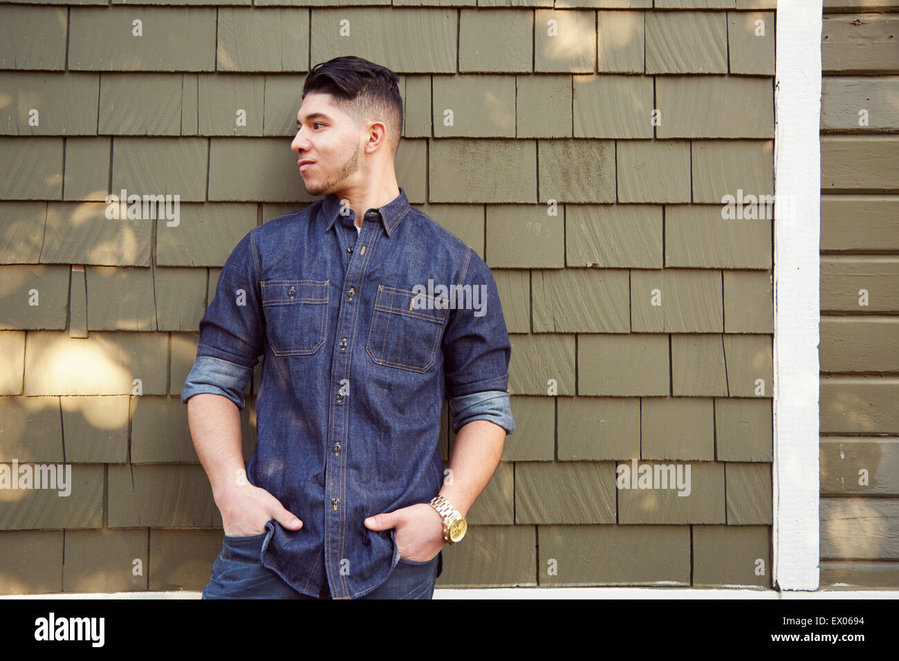 Young man by wall wearing denim shirt Stock Photo