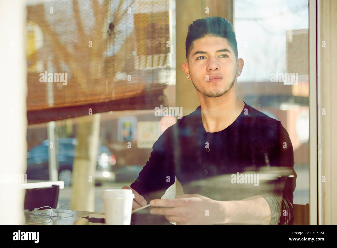 Young man in cafe looking through window Stock Photo