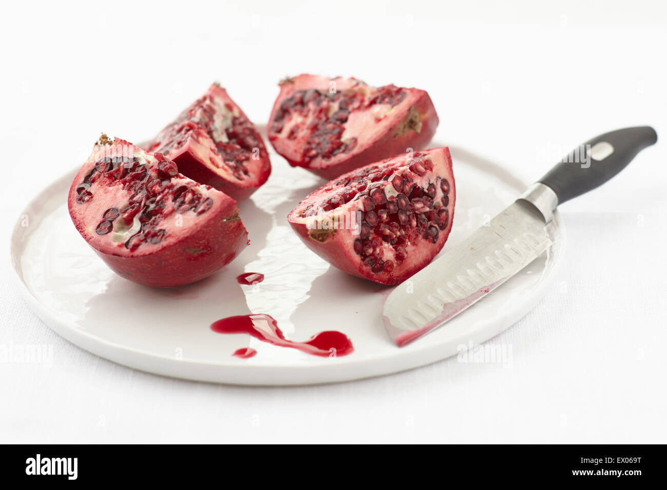 Still life of quartered pomegranate on plate Stock Photo