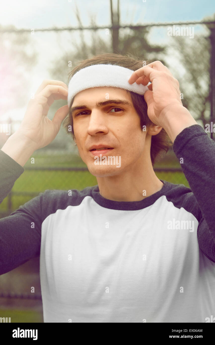 Portrait of mid adult male soccer player adjusting headband on soccer pitch Stock Photo