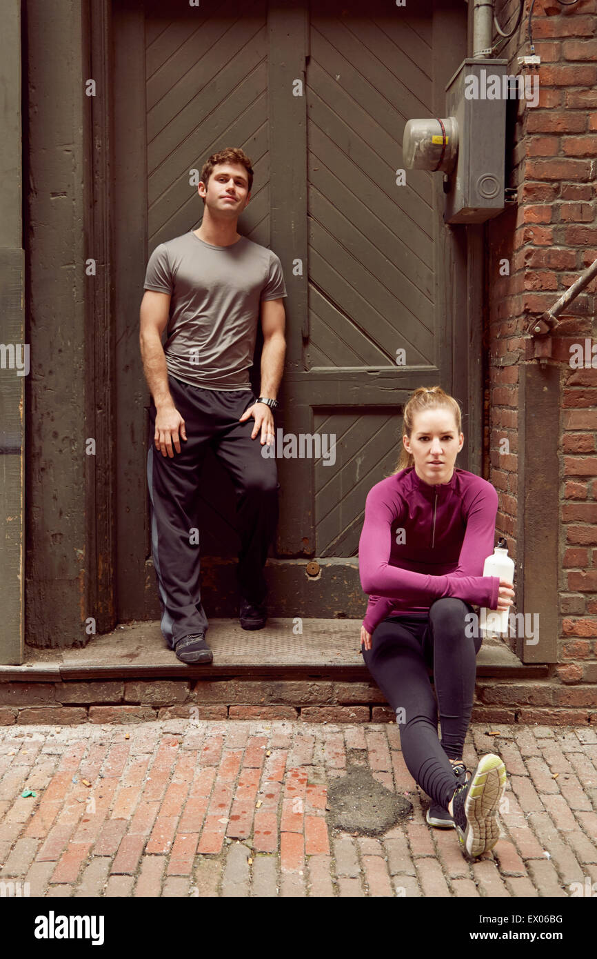 Portrait of young male and female runners in alleyway Stock Photo