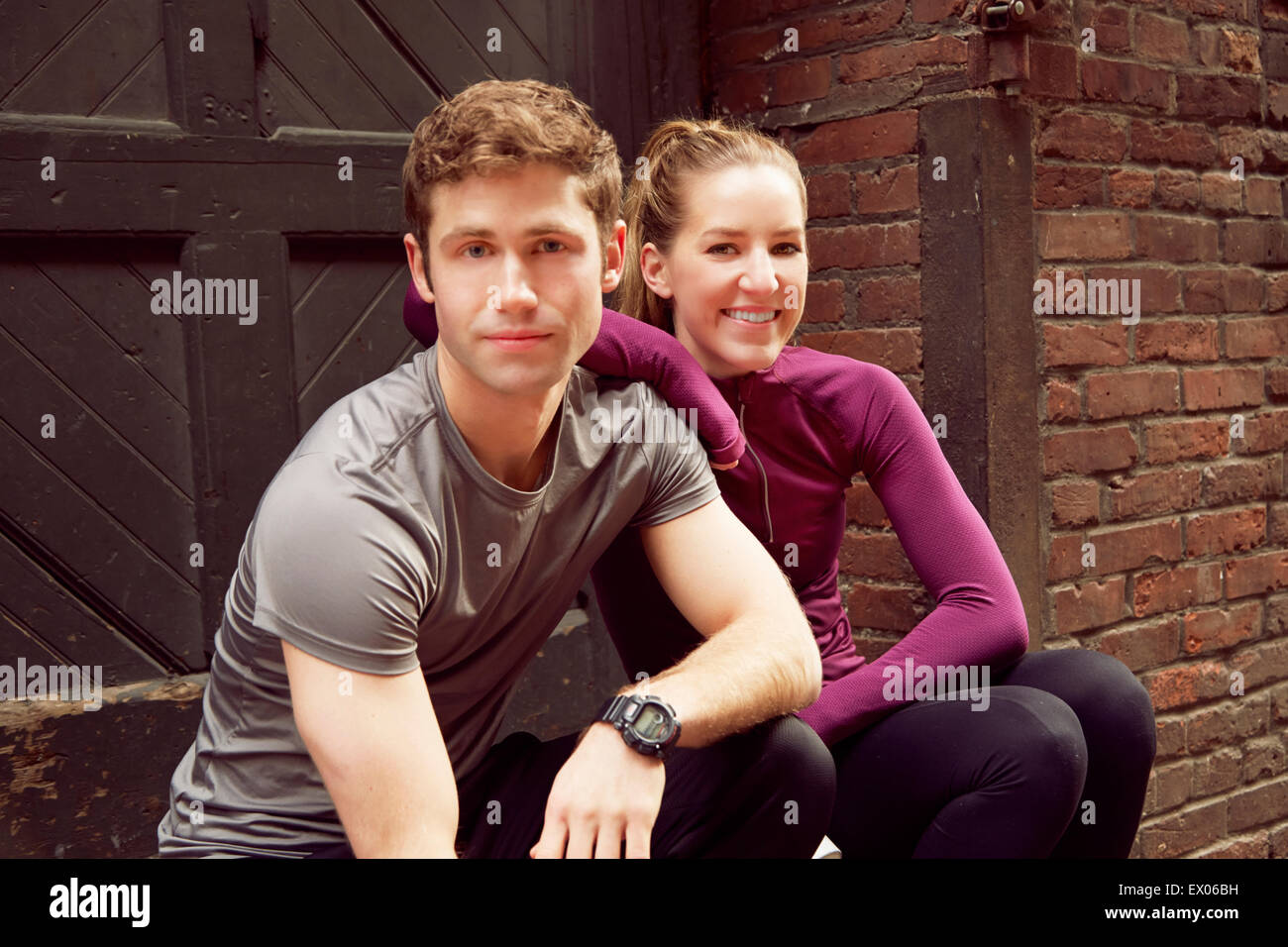 Portrait of young male and female runners sitting on alley step Stock Photo