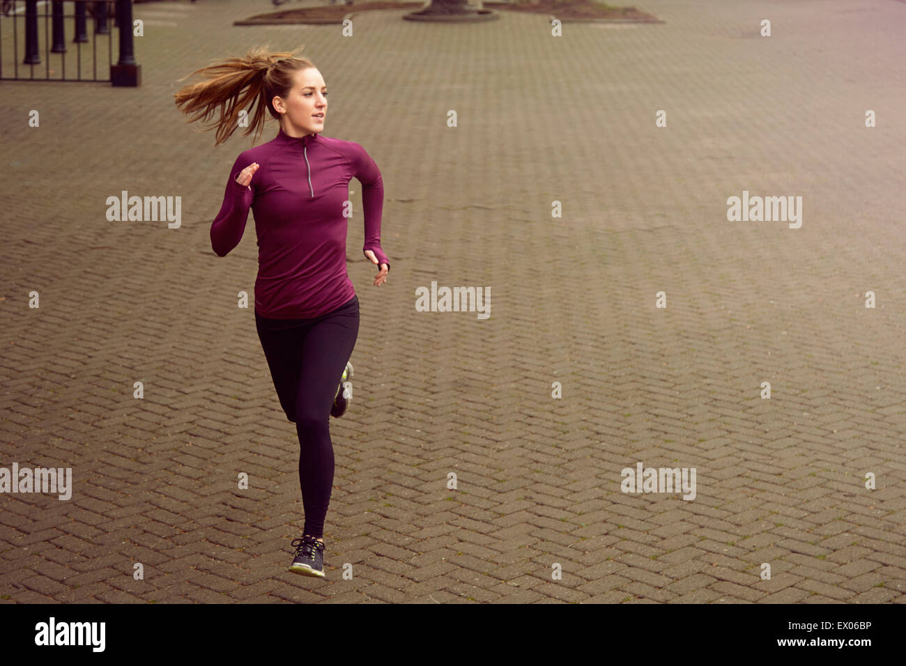 Young woman running along sidewalk Stock Photo