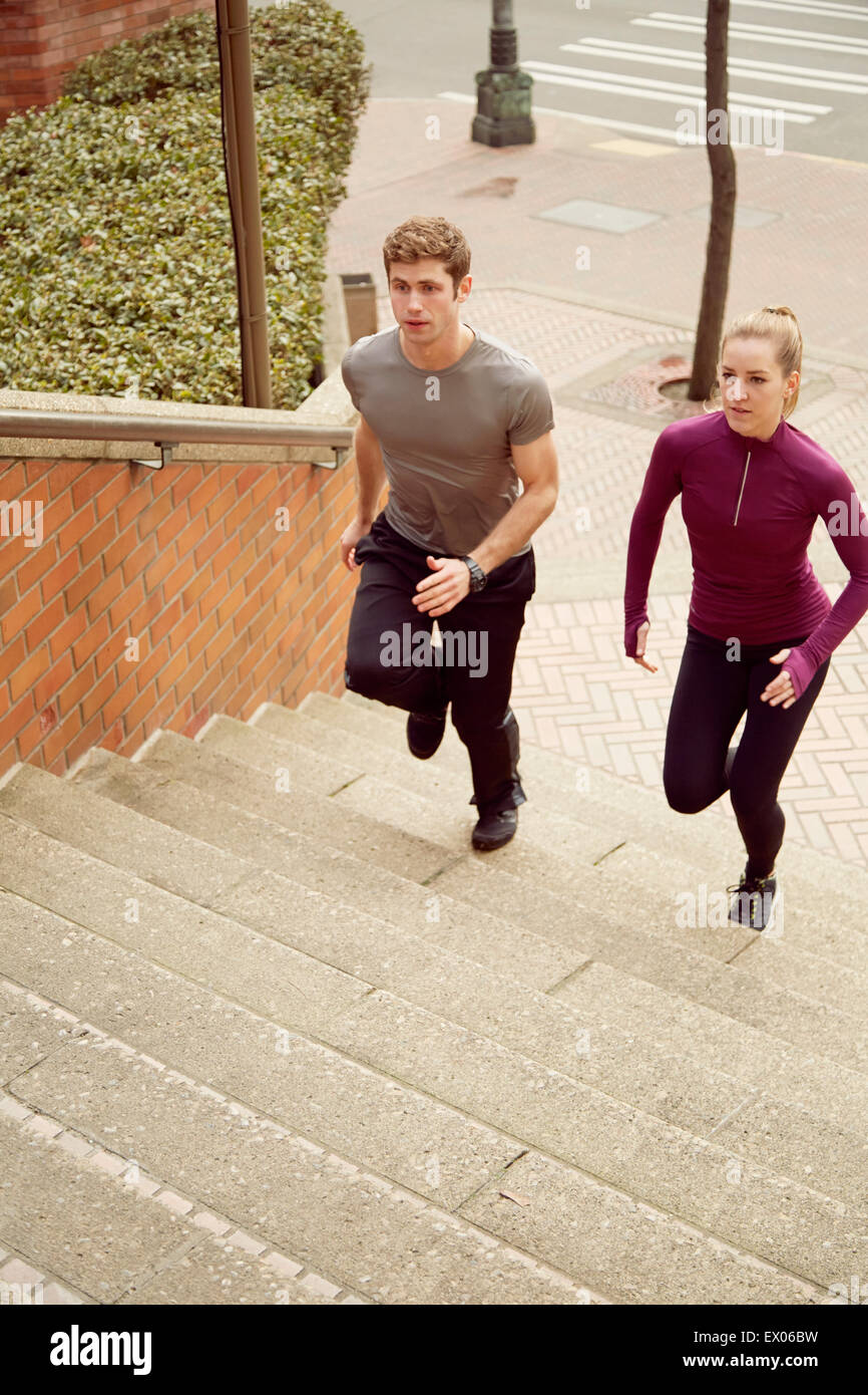 Young man and woman running up city stairway Stock Photo