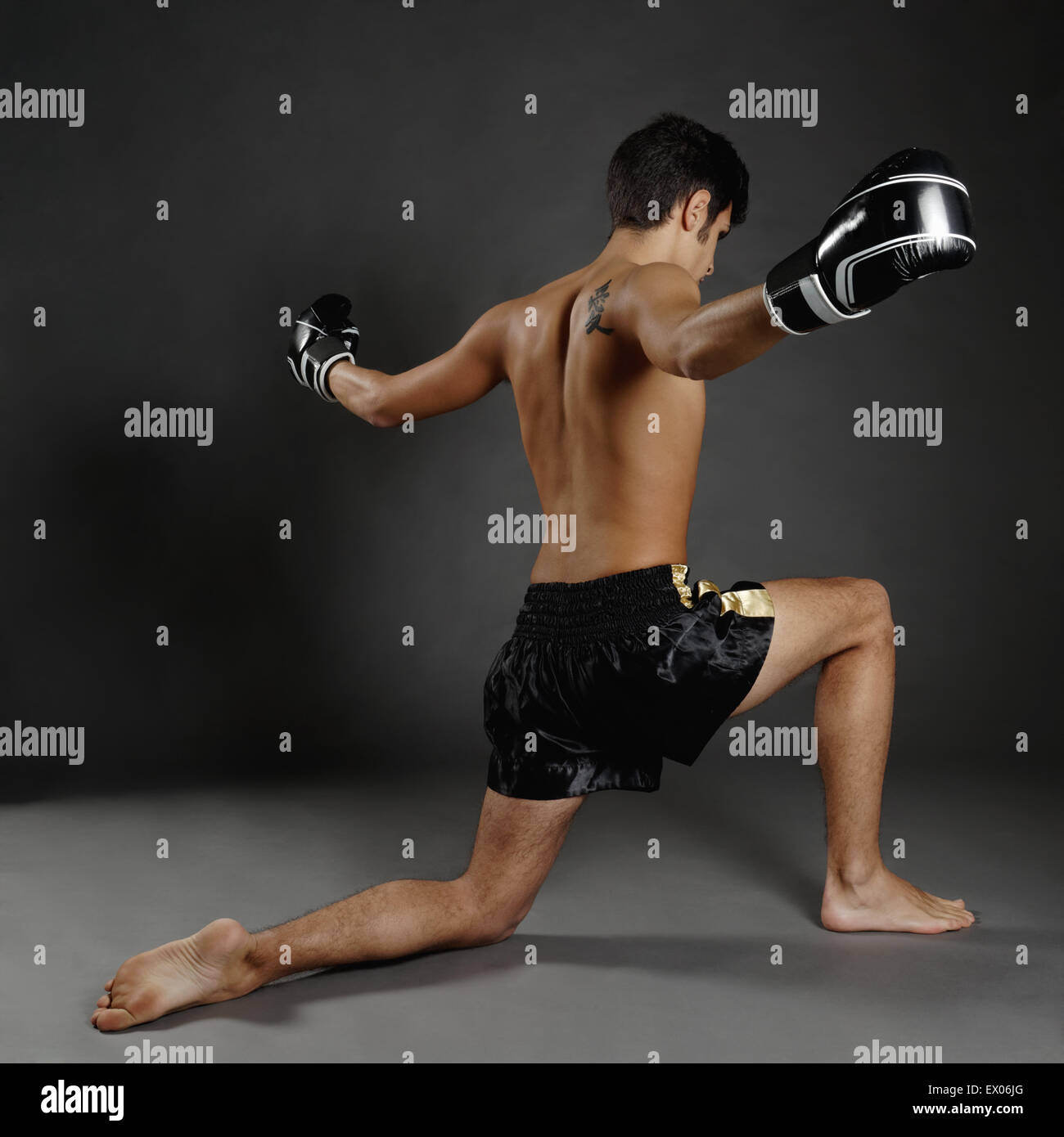 Rear view of young man in boxing gloves poised on one knee Stock Photo