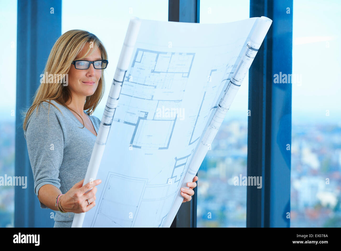 Mature female architect looking at plans in skyscraper office, Brussels, Belgium Stock Photo