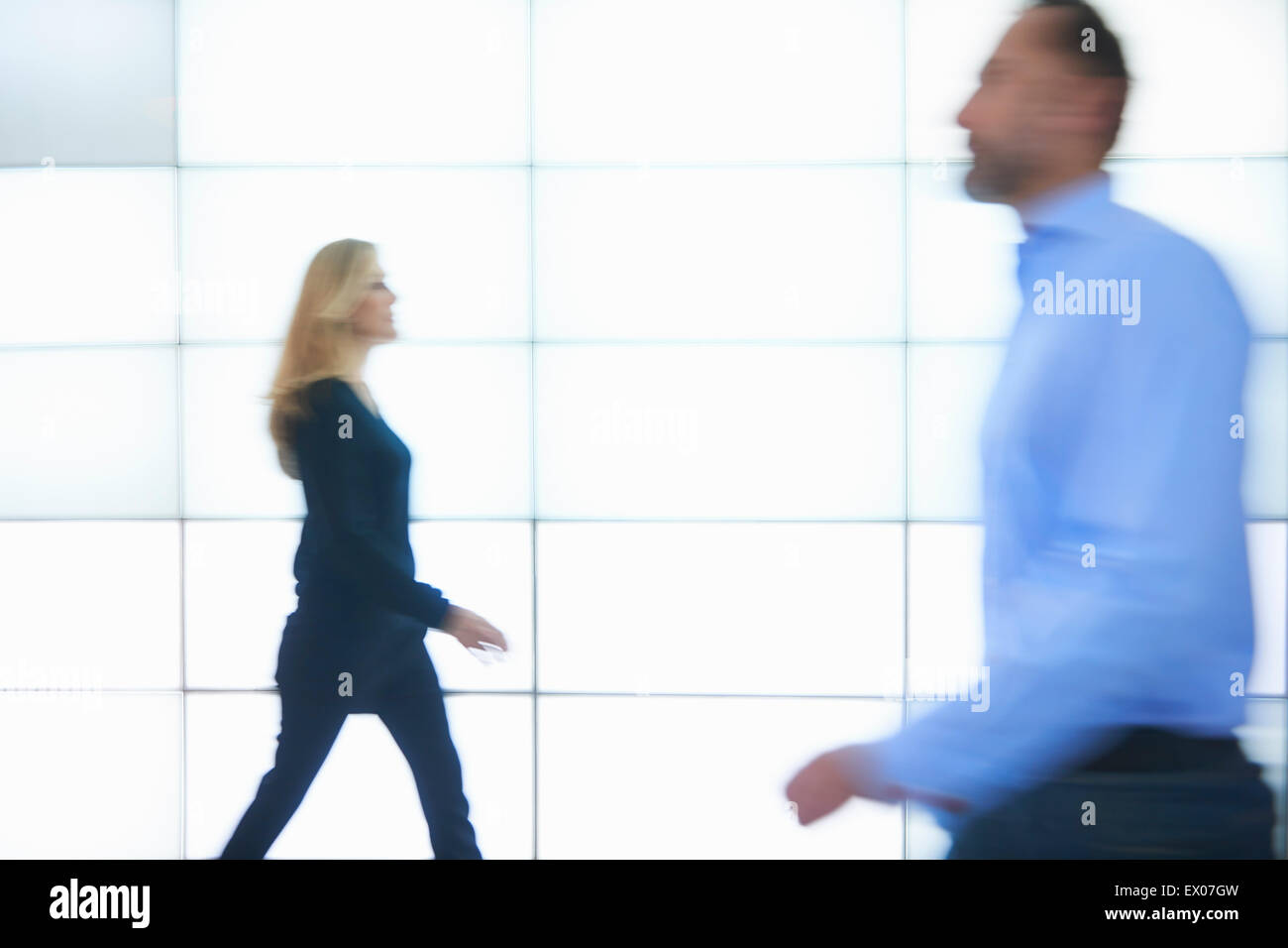 Man and woman walking past backlit wall panels Stock Photo