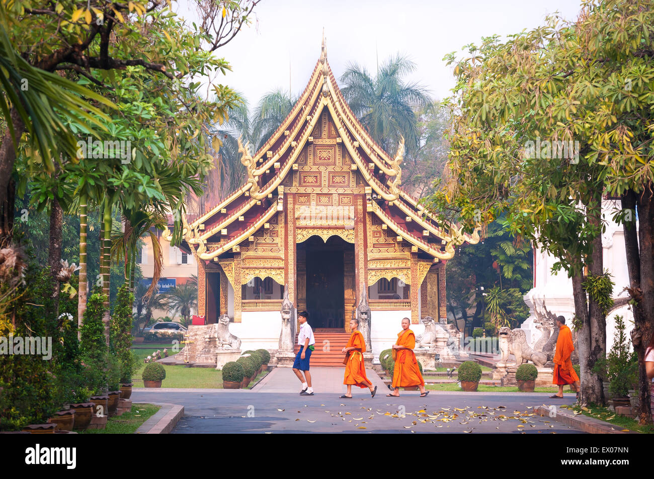 Monks and schoolboys walk past Viharn Lai Kham at Wat Phra Singh, Chiang Mai, Thailand Stock Photo