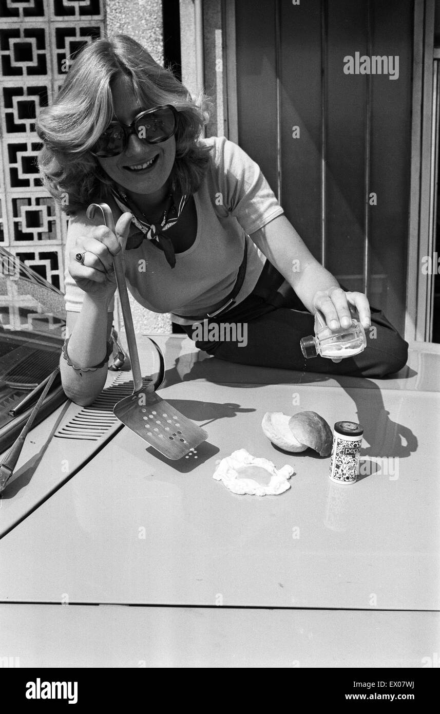 A woman cooks an egg on a car bonnet during the 1976 heatwave. 25th June 1976. Stock Photo