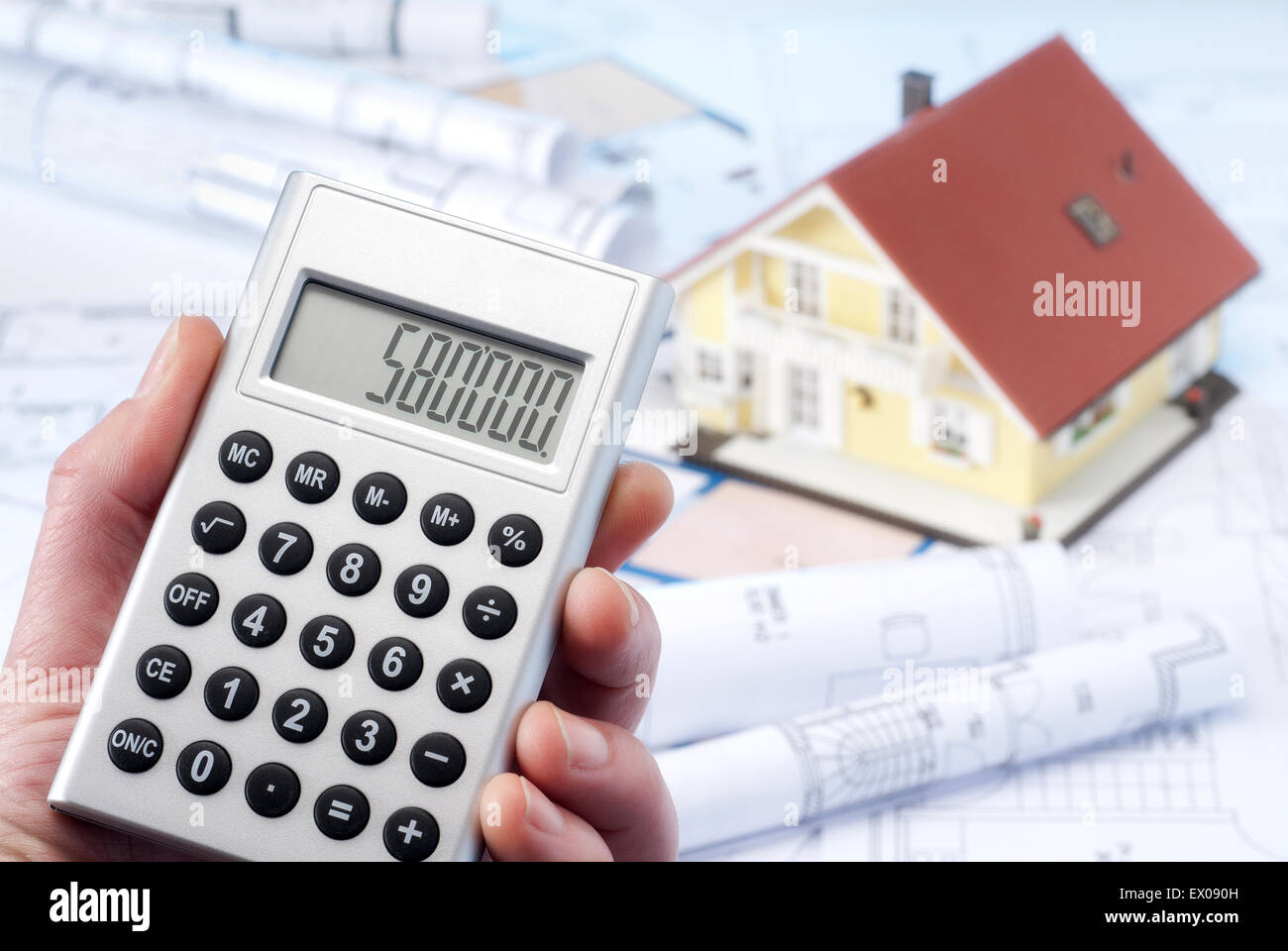 Calculator with a large sum, architectural model and blueprints. Stock Photo