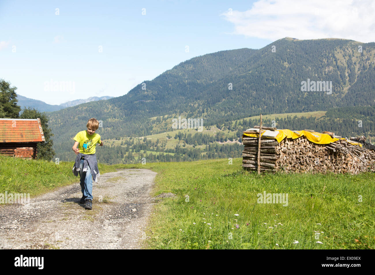 Boy running along dirt track in mountain landscape,  Eckbauer bei Garmisch, Bavaria, Germany Stock Photo