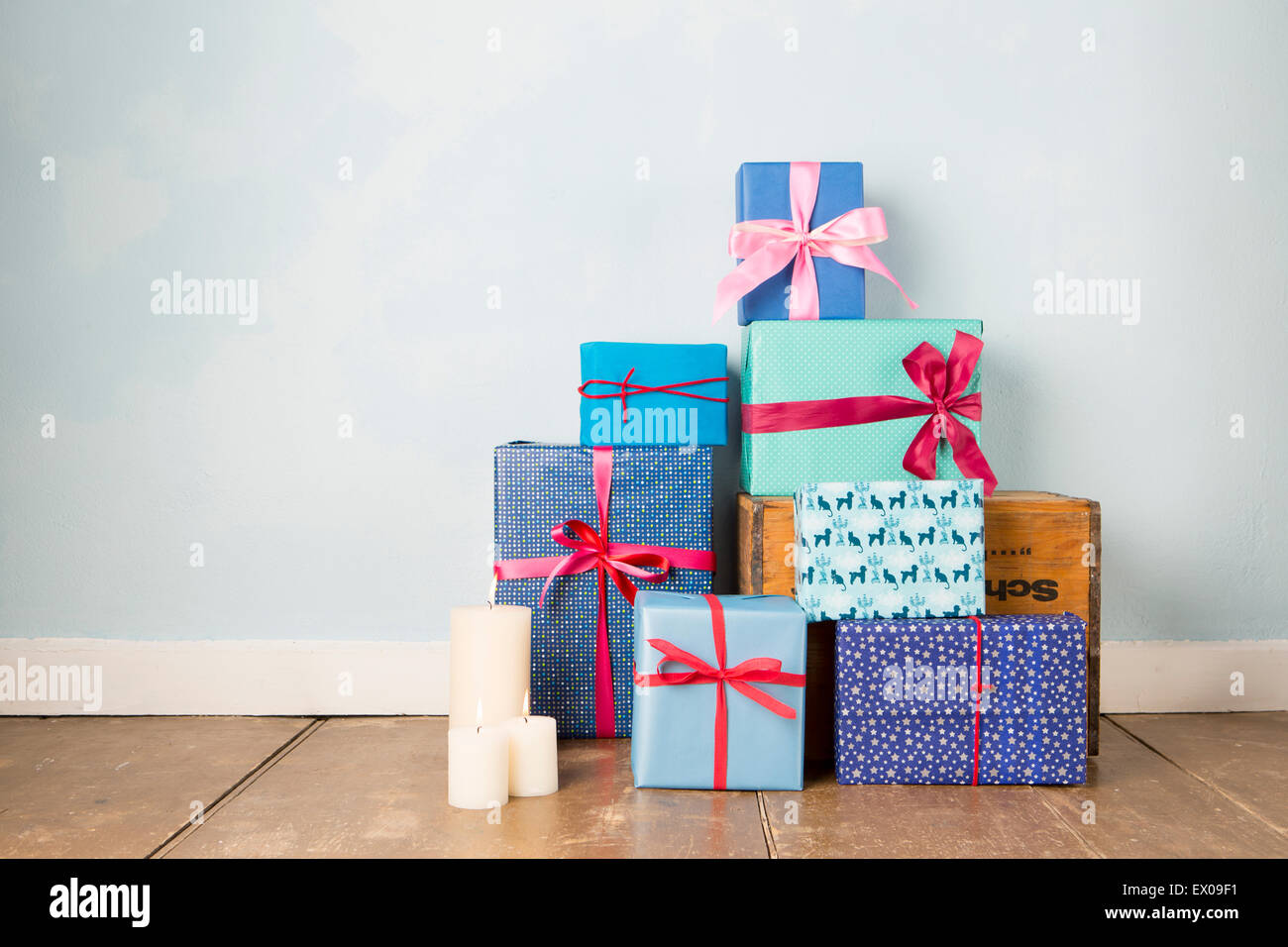 Candles and stack of wrapped christmas gifts on wooden floor Stock Photo