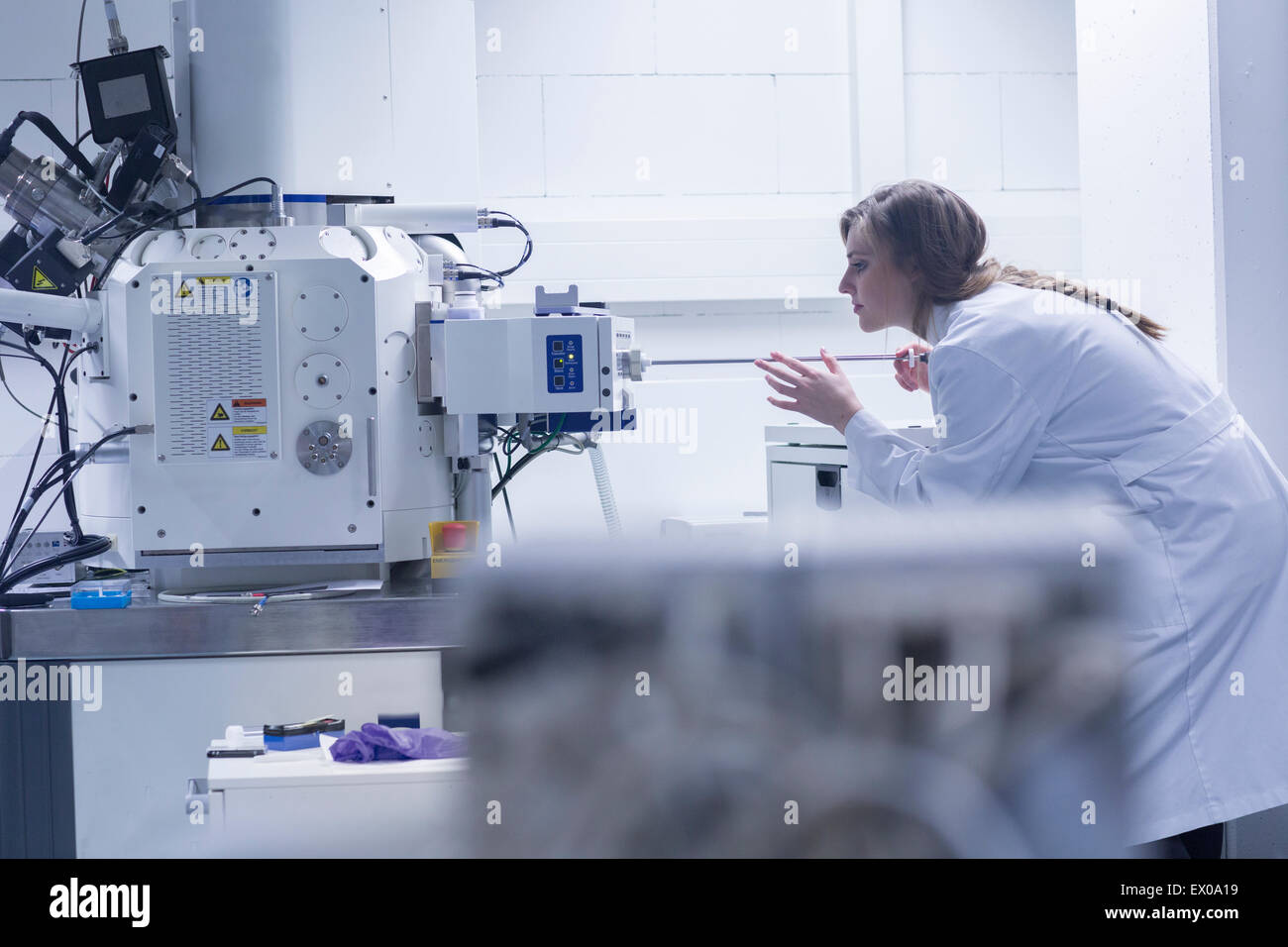 Young female scientist in lab using scanning electron microscope Stock Photo