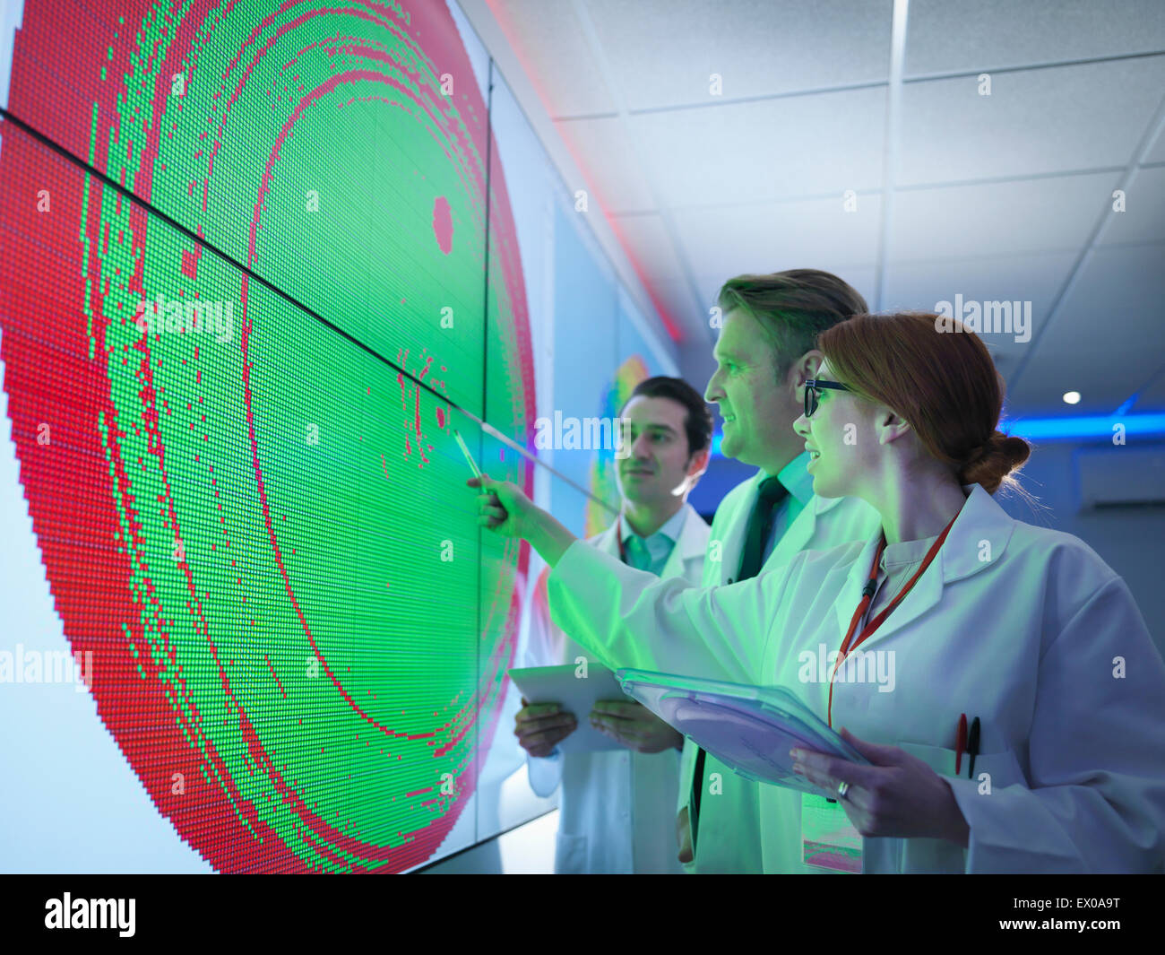 Scientists studying graphical display of silicon wafer on screens Stock Photo