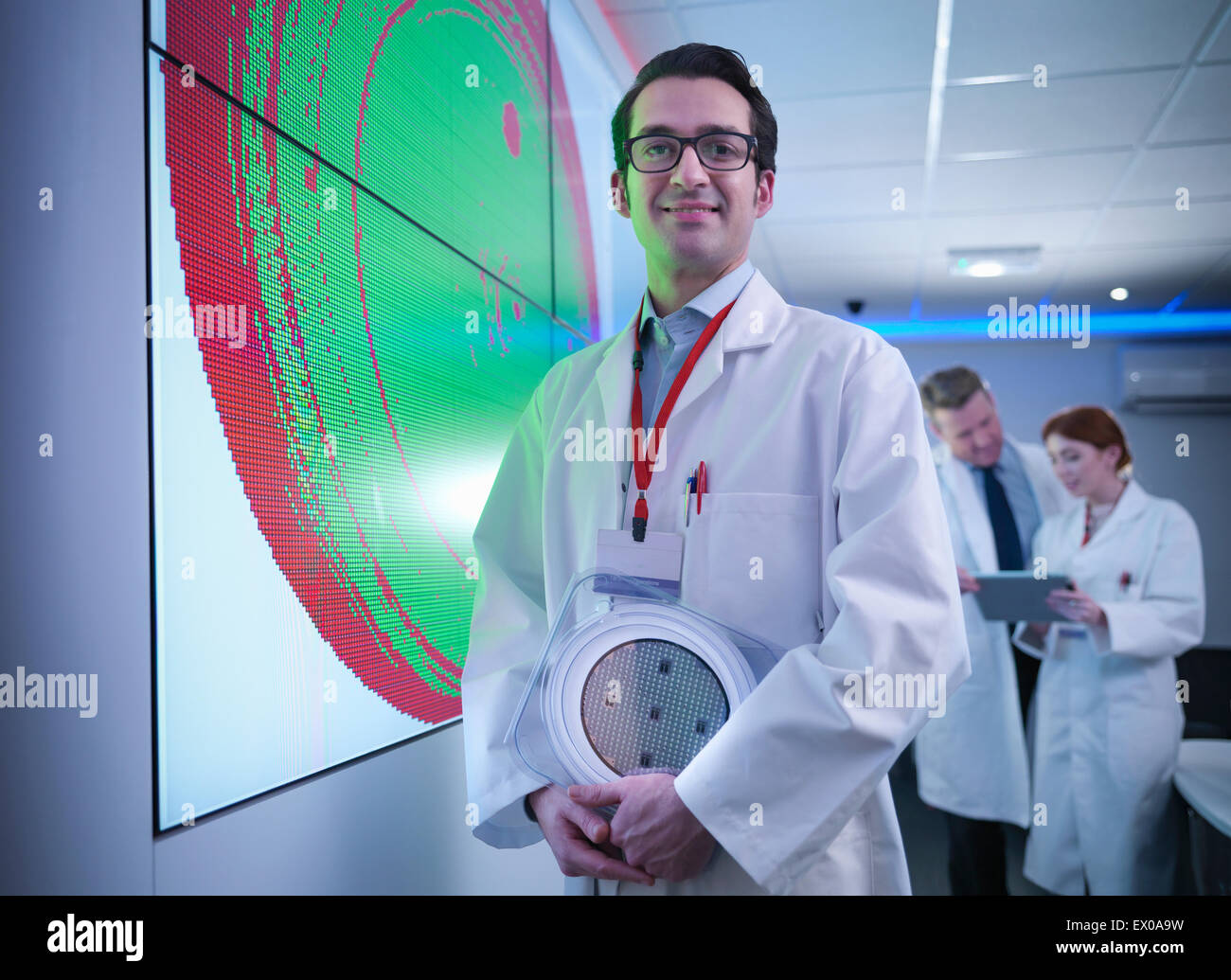 Portrait of scientist in front of graphical display of silicon wafer on screens Stock Photo