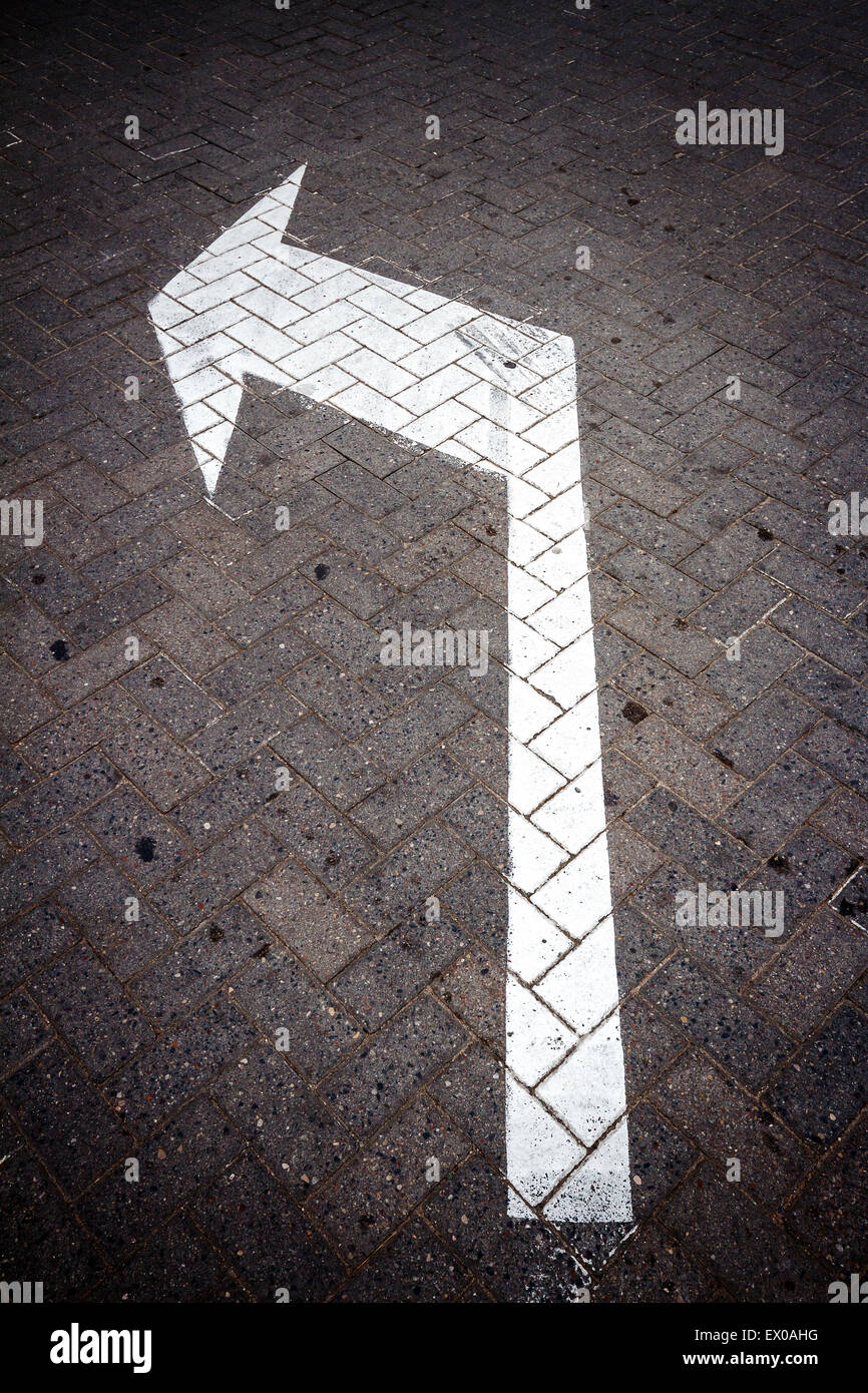 White directional arrow sign on a road Stock Photo - Alamy