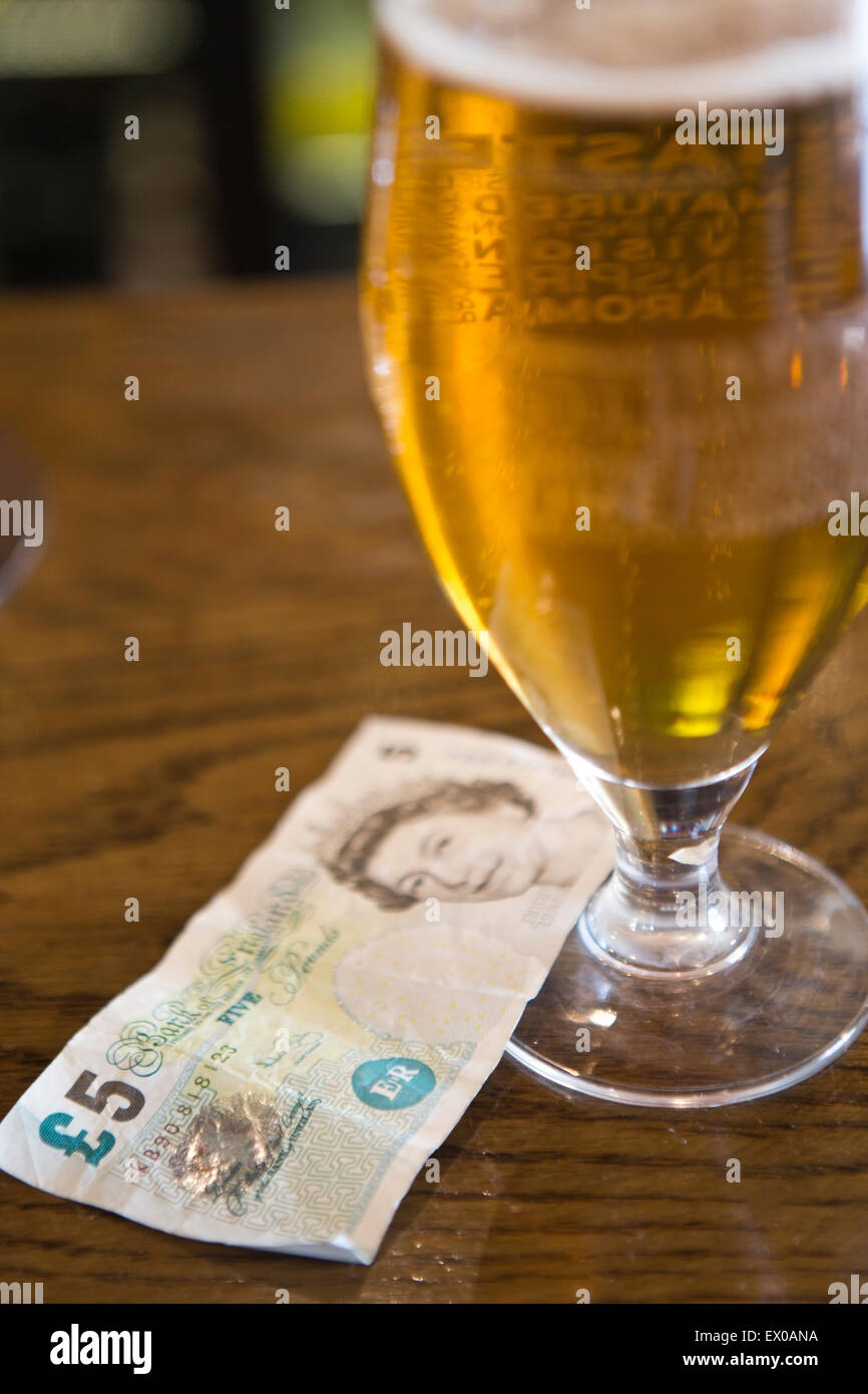 A five pound note next to a pint of lager Stock Photo