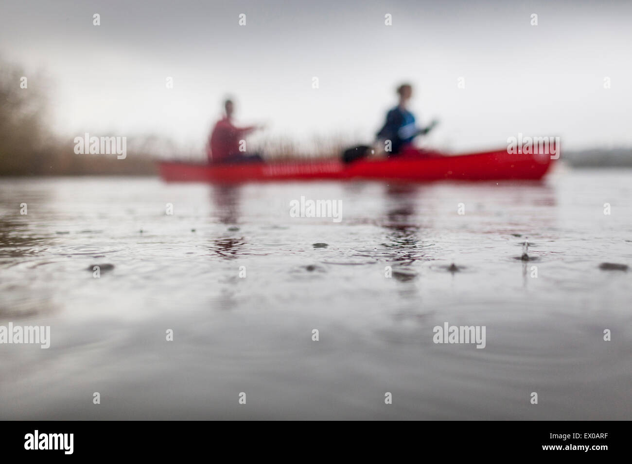 Two people canoeing in rain Stock Photo Alamy