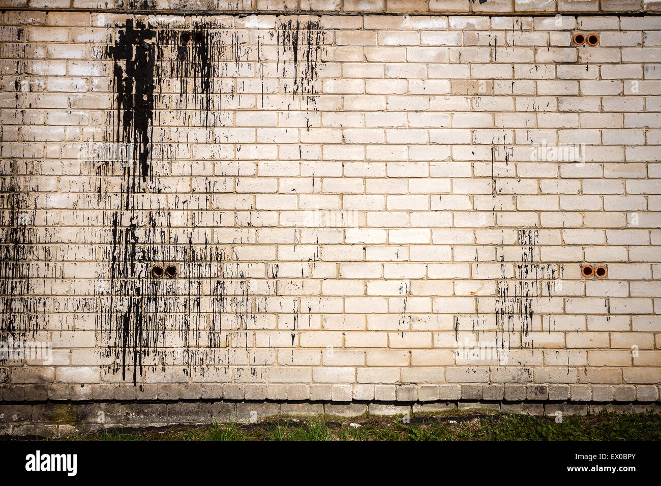 Old weathered wall of bricks with a splash of black tar Stock Photo