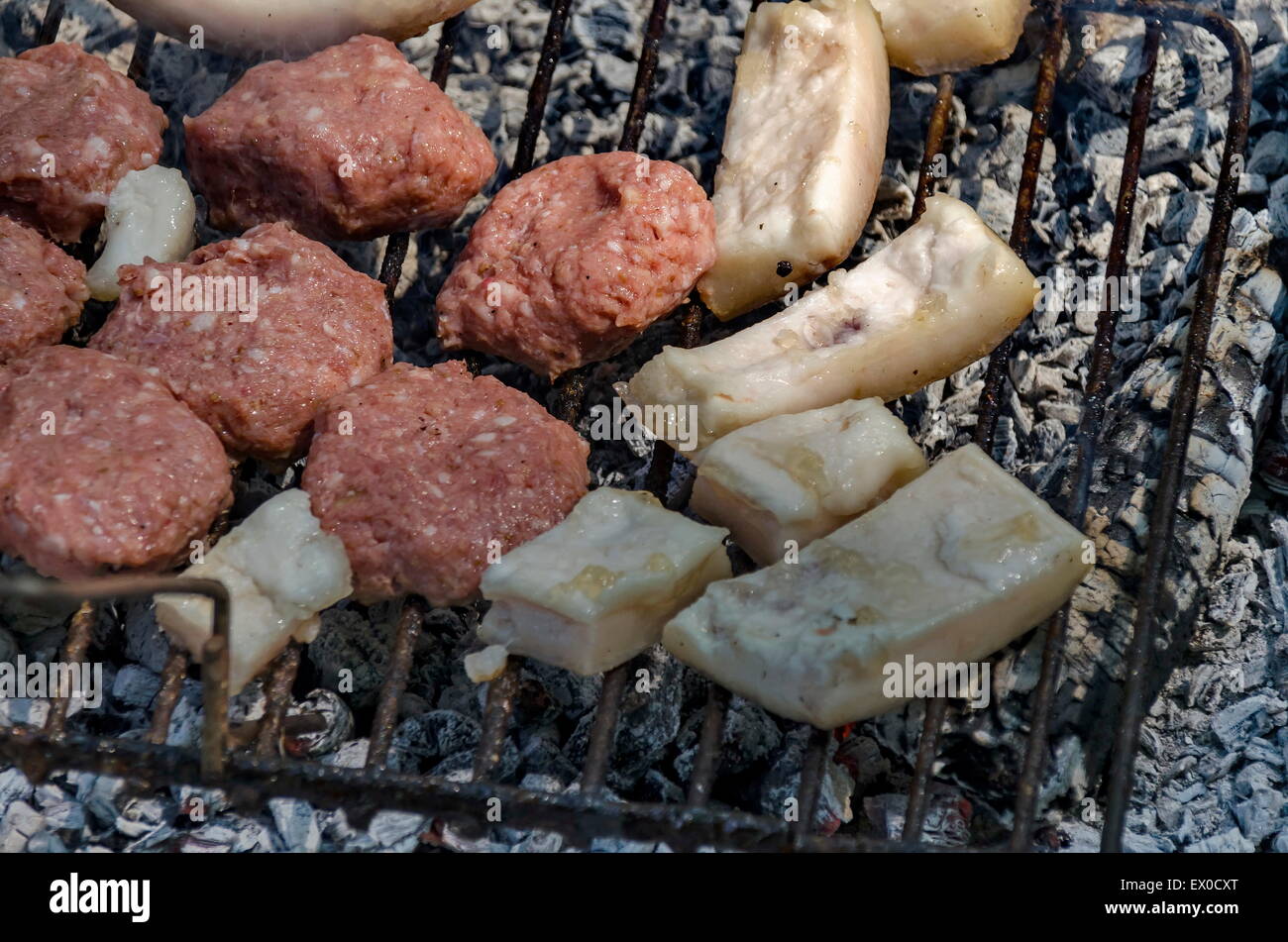Steaks cooking over hot coals from open fire Stock Photo