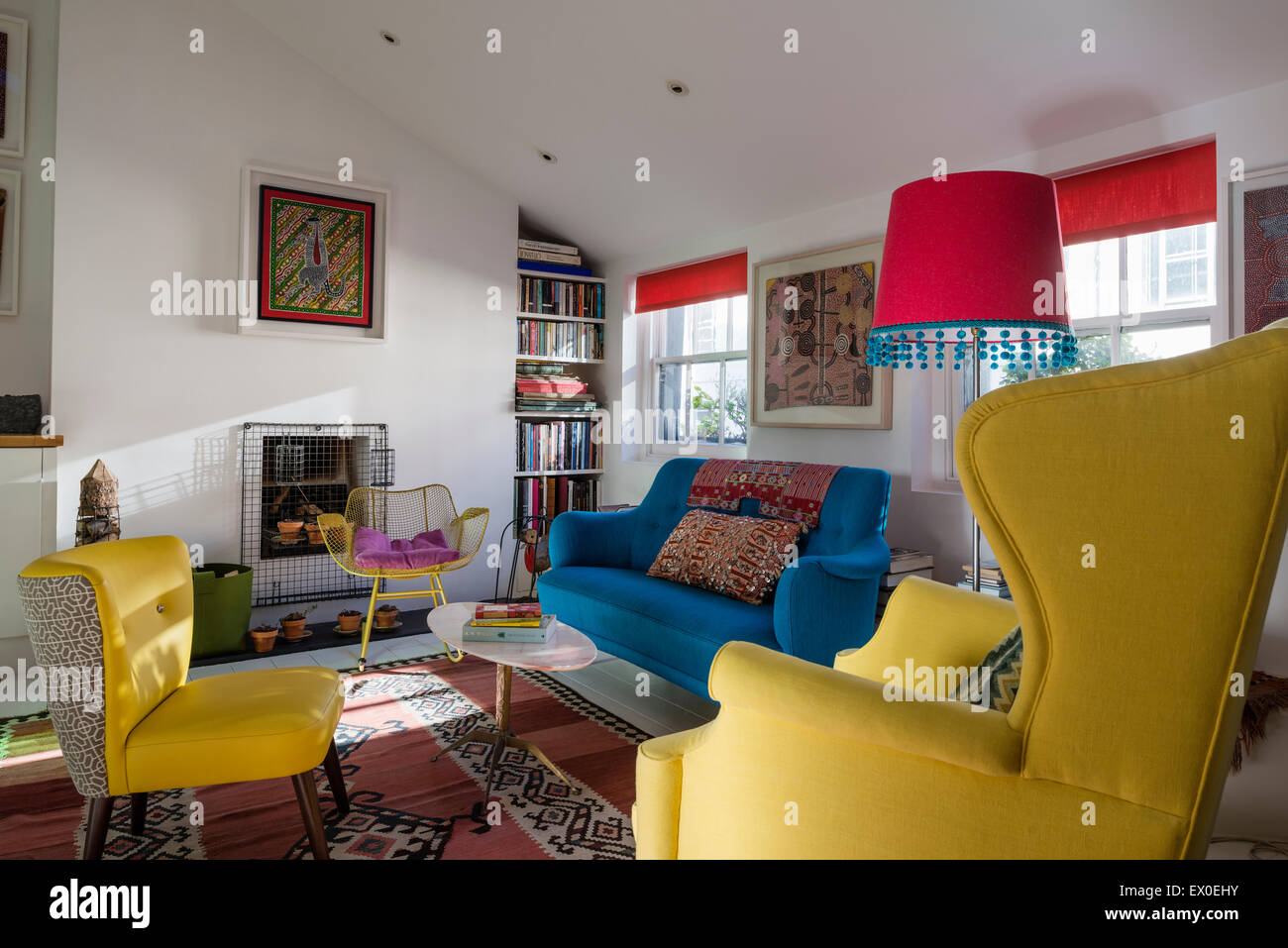 Bold blue sofa, Julep chair and Eames wire rocking chair in living room with aboriginal wall art Stock Photo