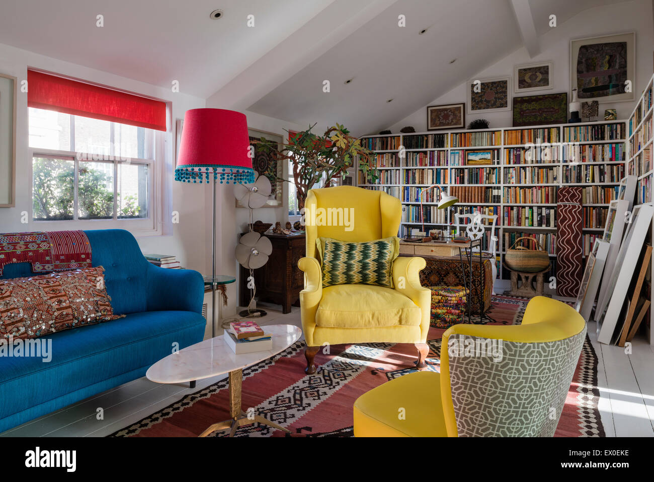 Yellow winged back armchair, Julep chair and bold blue sofa in living room  with uzbek kilim, aboriginal art and inbuilt book she Stock Photo - Alamy