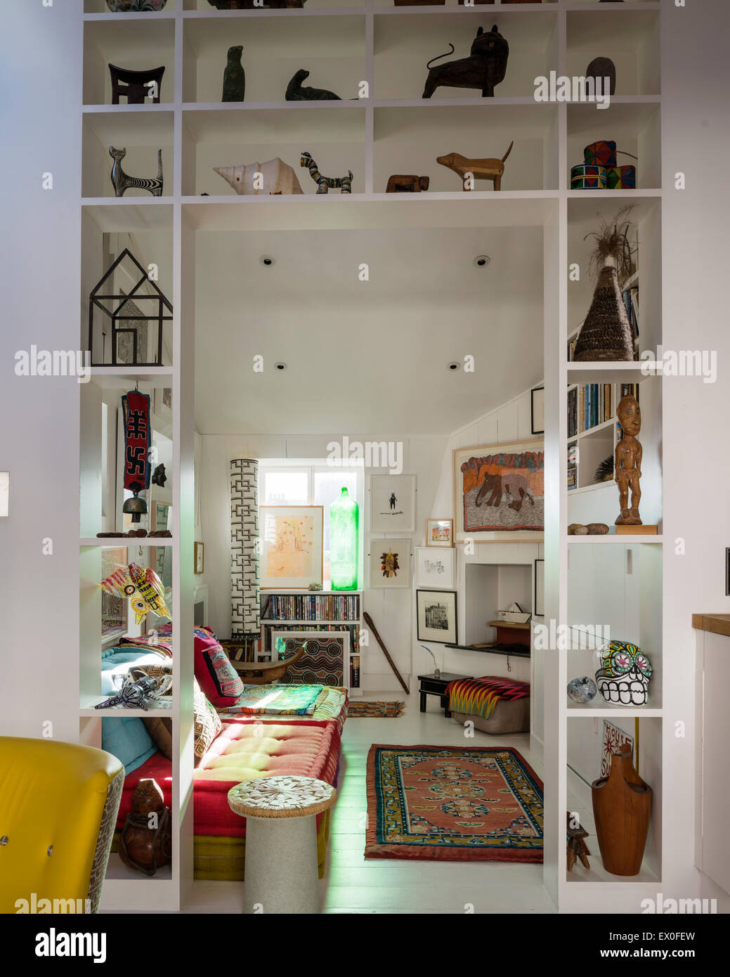 Small sculptures and artefacts on open shelving in room with uzbek rug Stock Photo