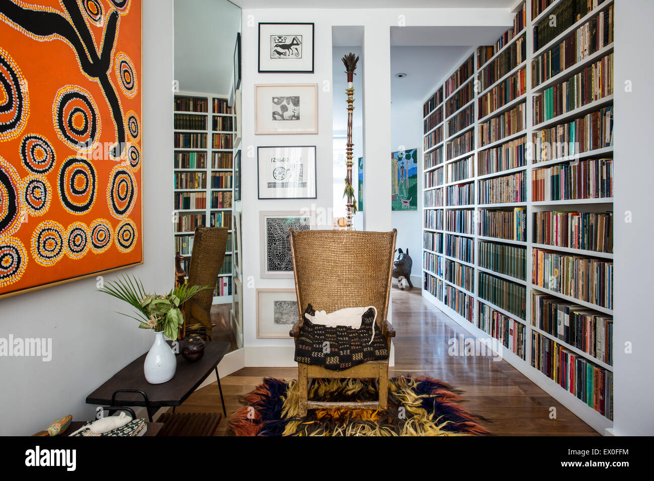 Antique Orkney chair in room with book shelving, shaggy rug and large aboriginal art piece Stock Photo