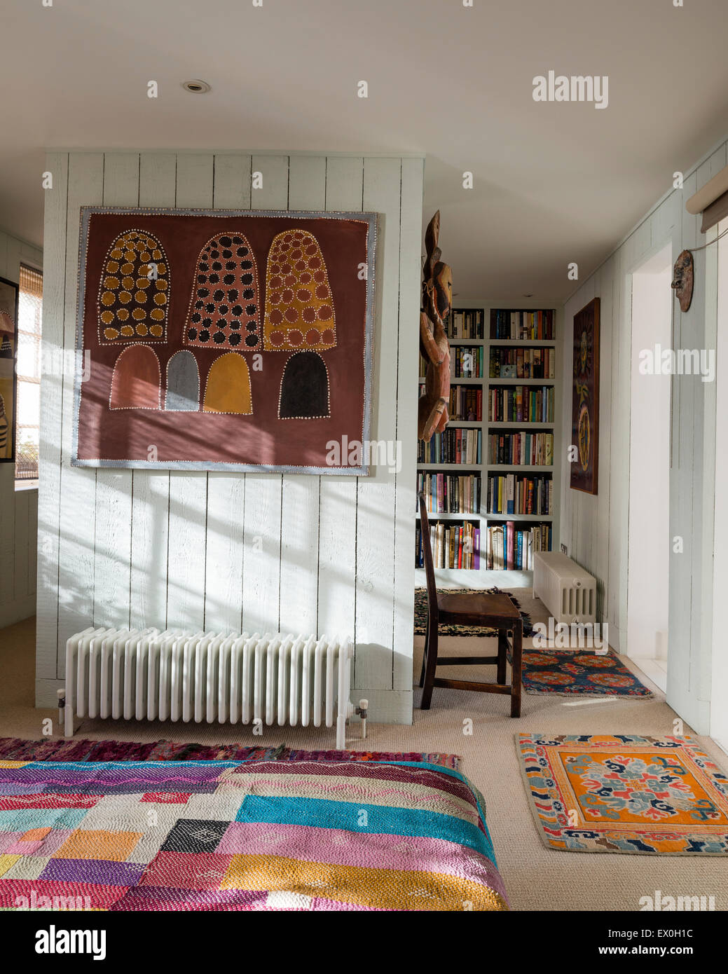 Painting on wall by aboriginal artist Queenie Mackenzie Nakarra in bedroom with antique quilt from Bihar, India Stock Photo