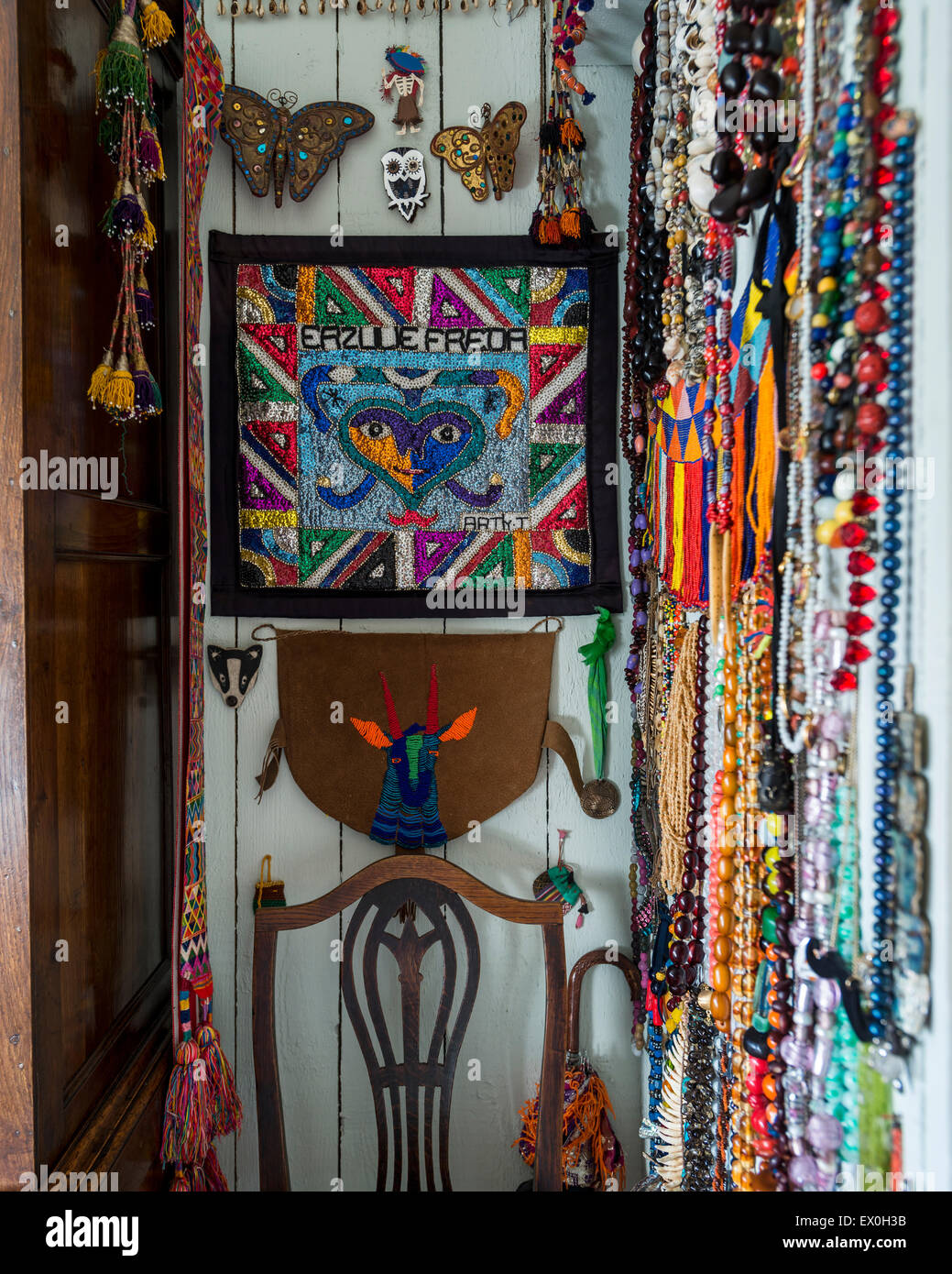 Necklaces and other ethnic jewelery and artwork hung from wall Stock Photo
