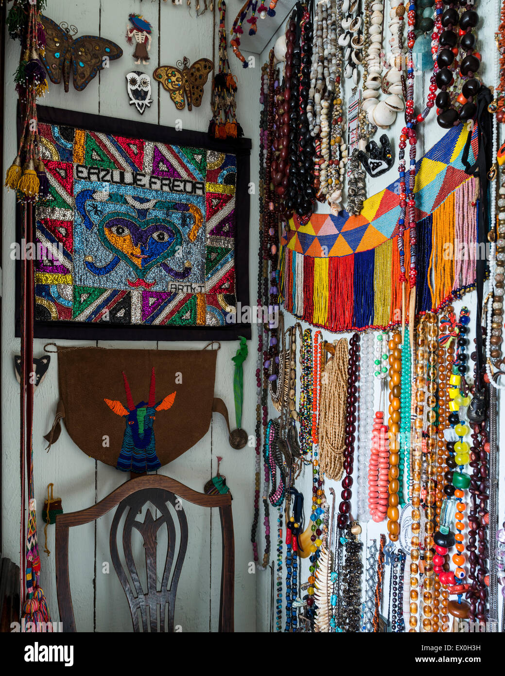 Necklaces and other ethnic jewellery and artwork hung from wall Stock Photo