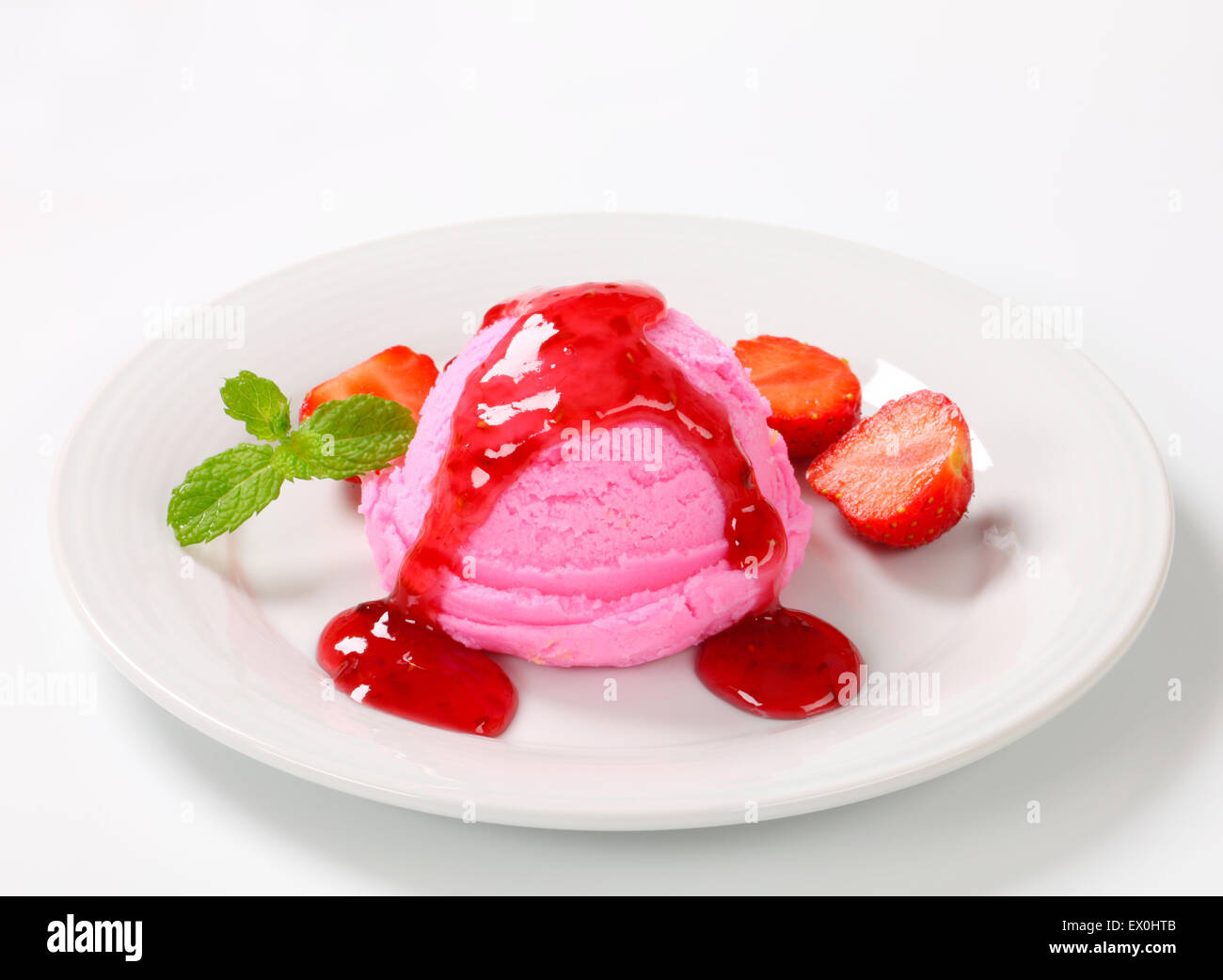 Scoop of pink ice cream with strawberry sauce Stock Photo