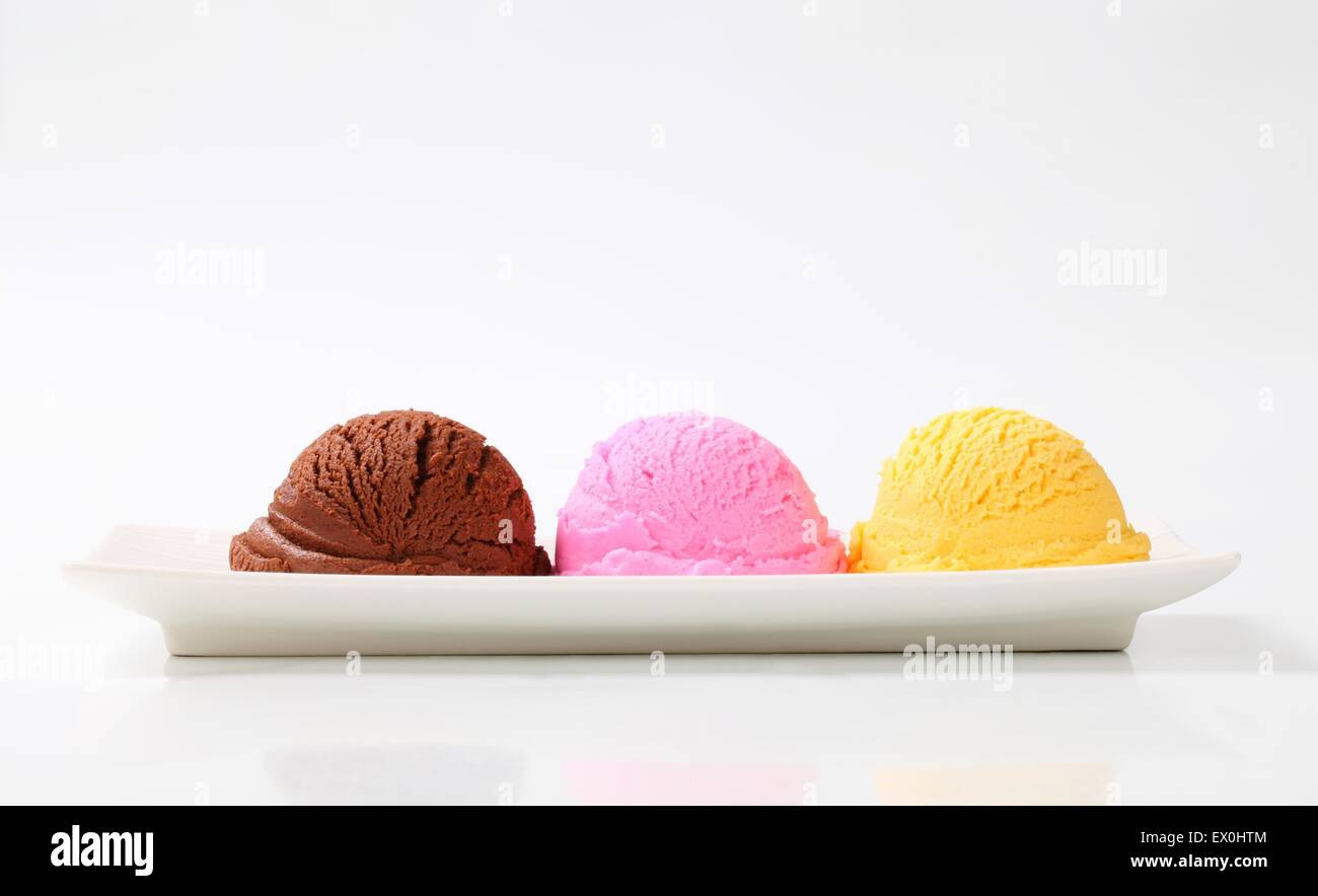 three flavored ice cream scoops on a pale blue plate, with