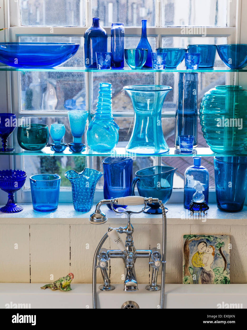 Collection of blue glassware on shelving in bathroom Stock Photo