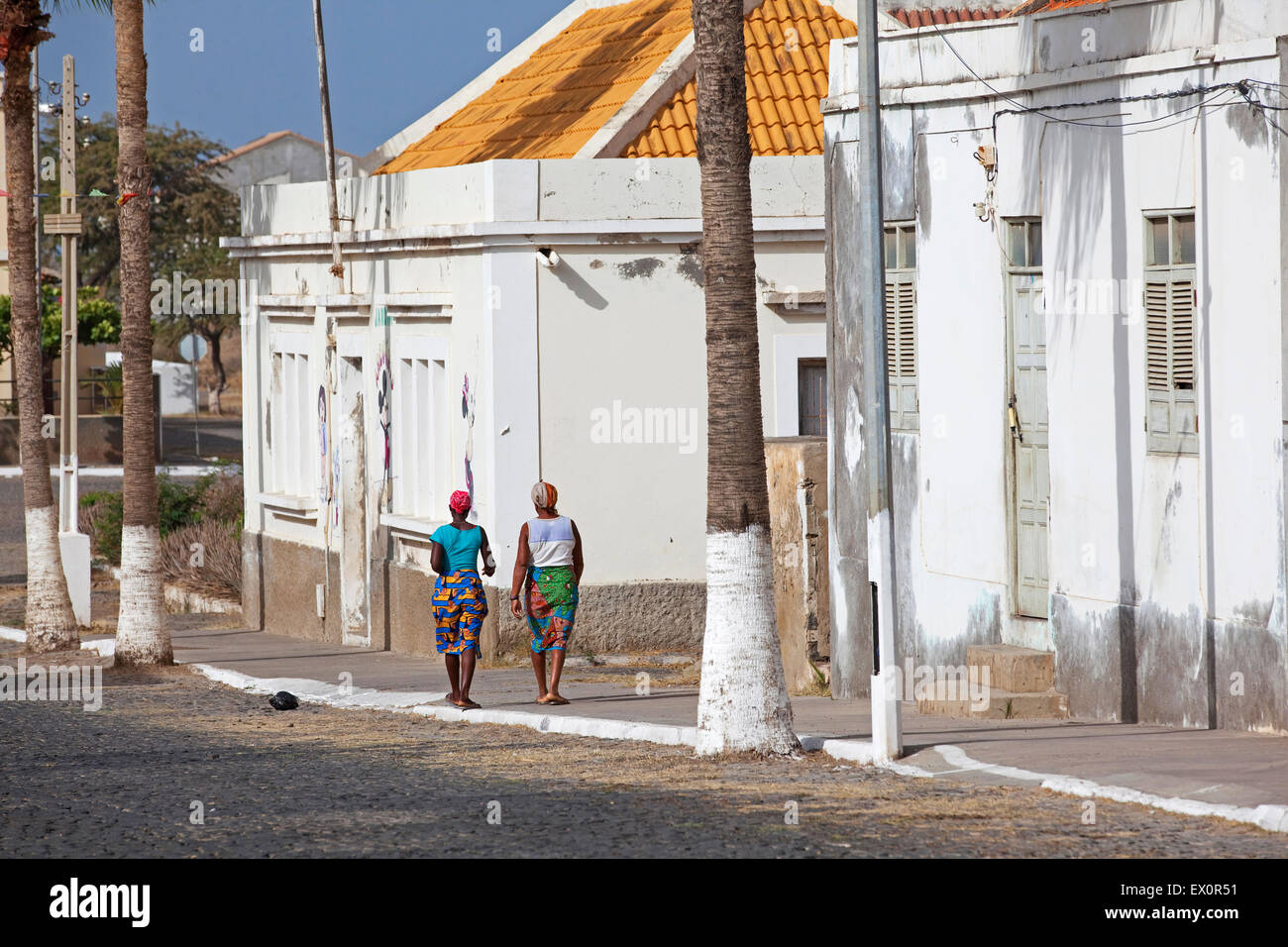 Creole women walking in street along white colonial buildings of the town Tarrafal on the island Santiago, Cape Verde, Africa Stock Photo