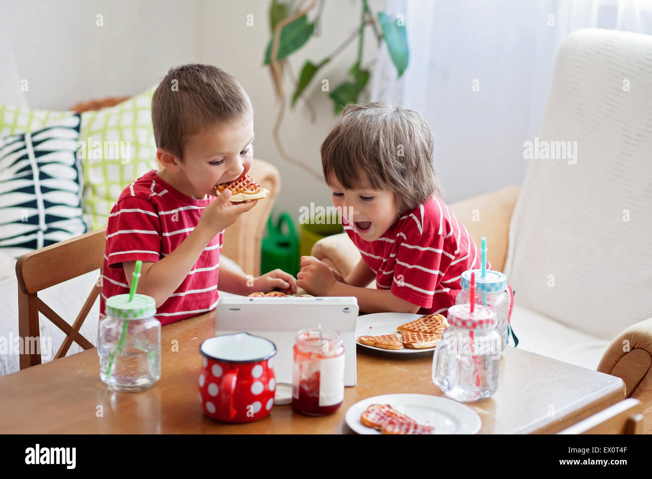 Two happy kids, two brothers, having healthy breakfast sitting at