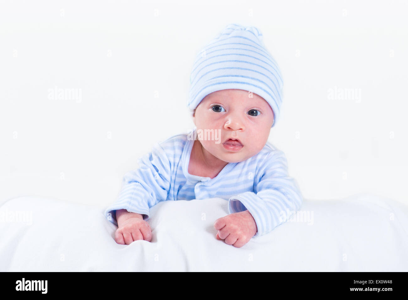 Adorable newborn baby boy playing on his tummy wearing a blue shirt and