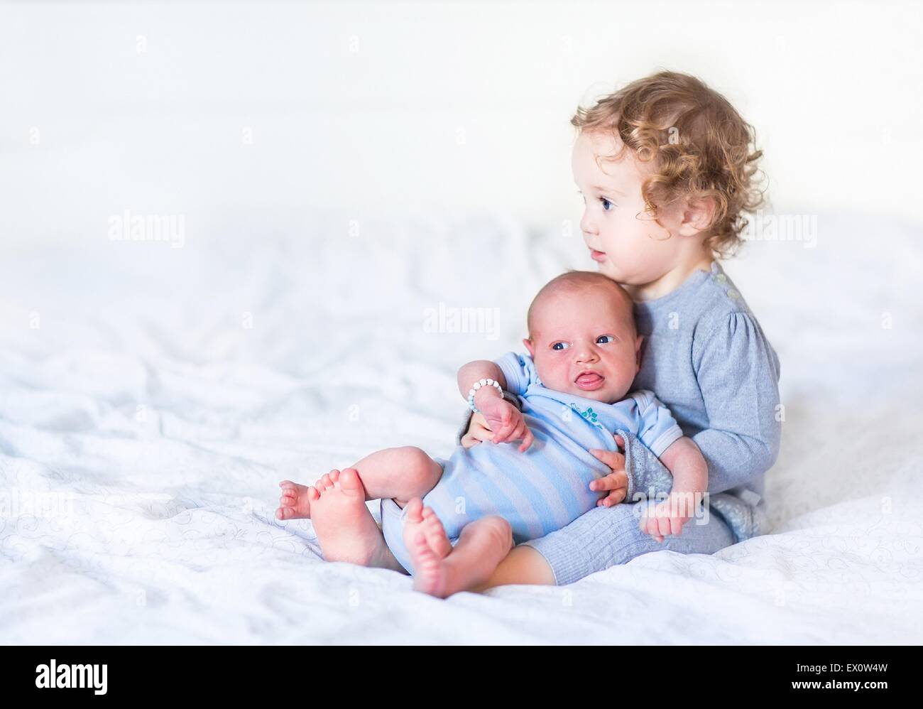 Adorable toddler girl holding her newborn baby brother Stock Photo - Alamy